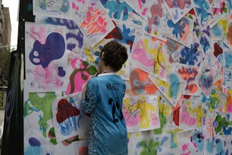 A child admiring colorful artwork on a wall.