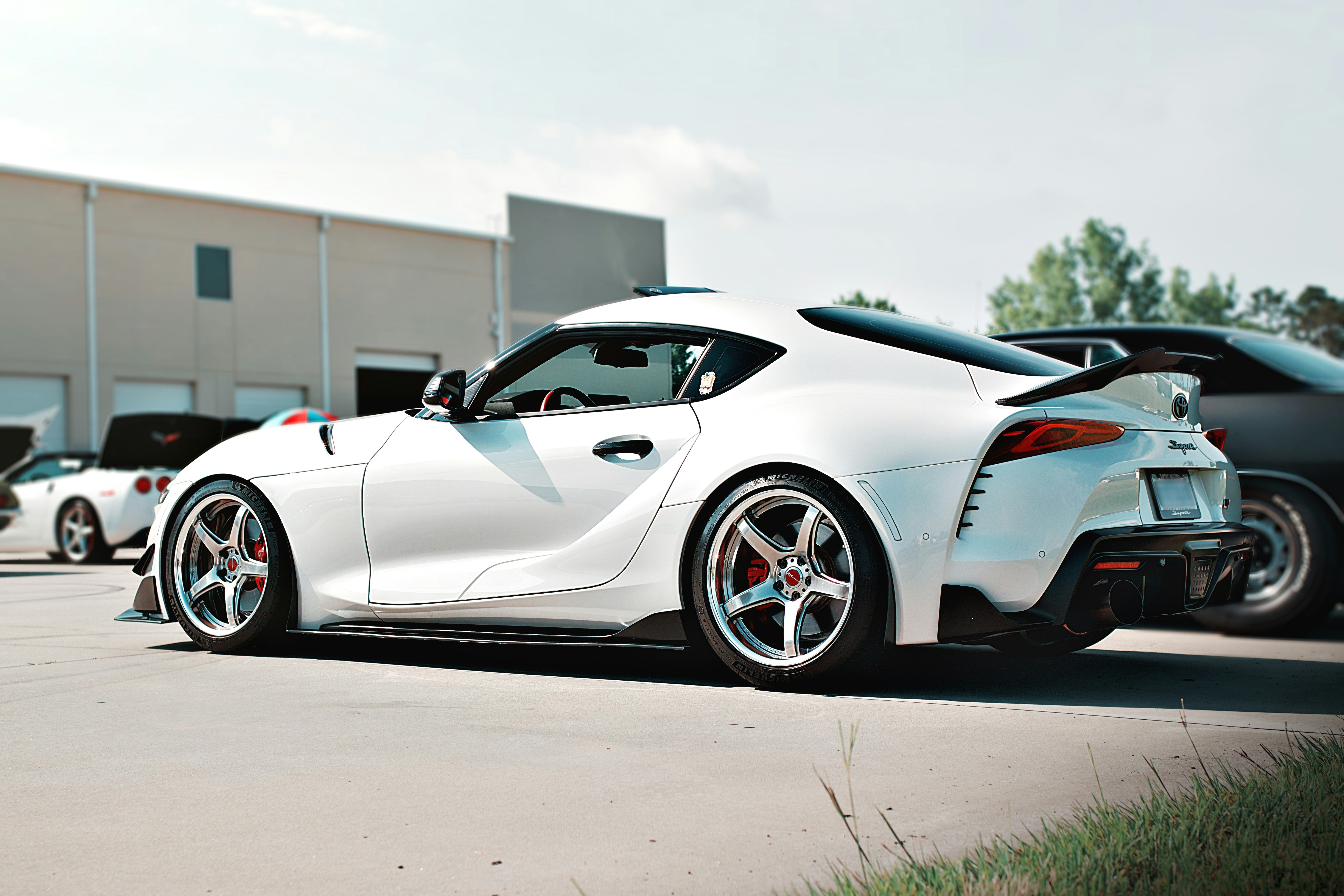A white toyota supra is parked outside.