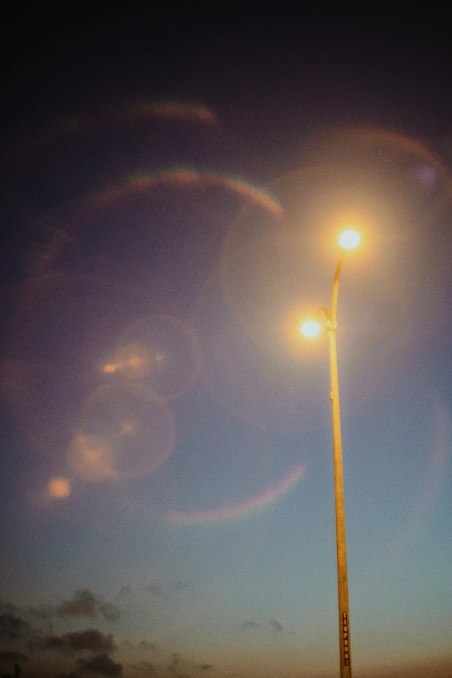 Streetlight glowing with glare against a dark sky