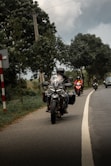 Motorcyclists ride down a road on a cloudy day.