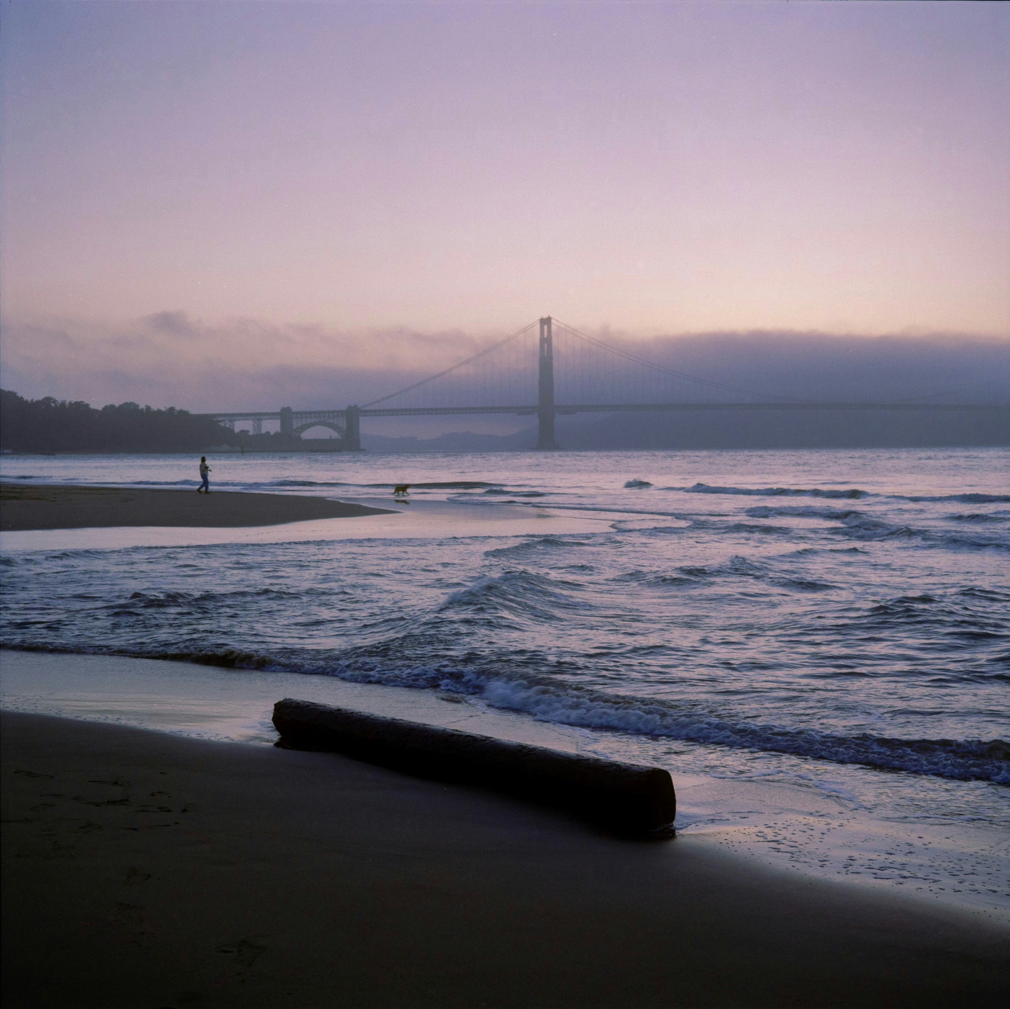 Beach scene with a bridge in the background.