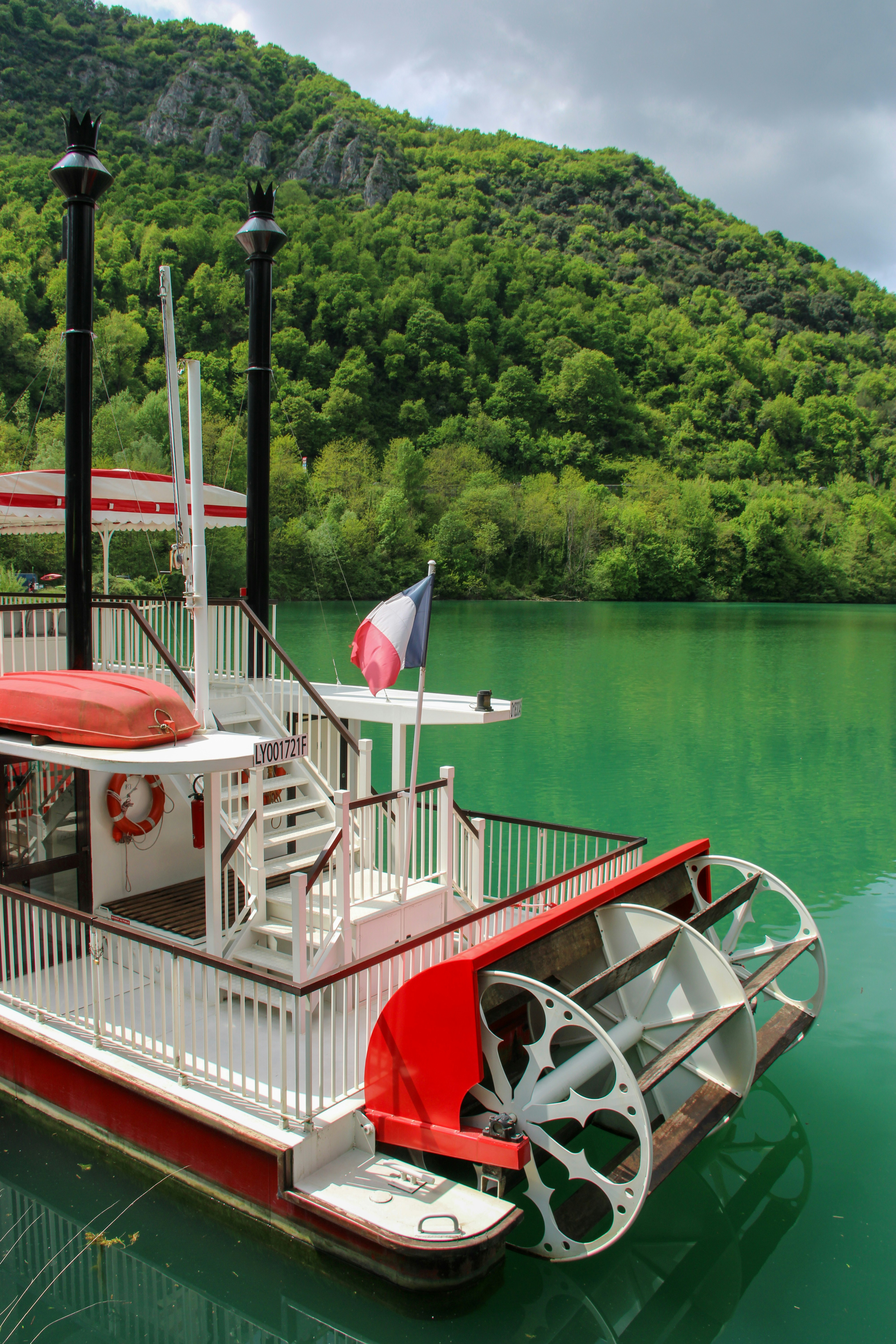Paddle steamer with french flag on a scenic lake.