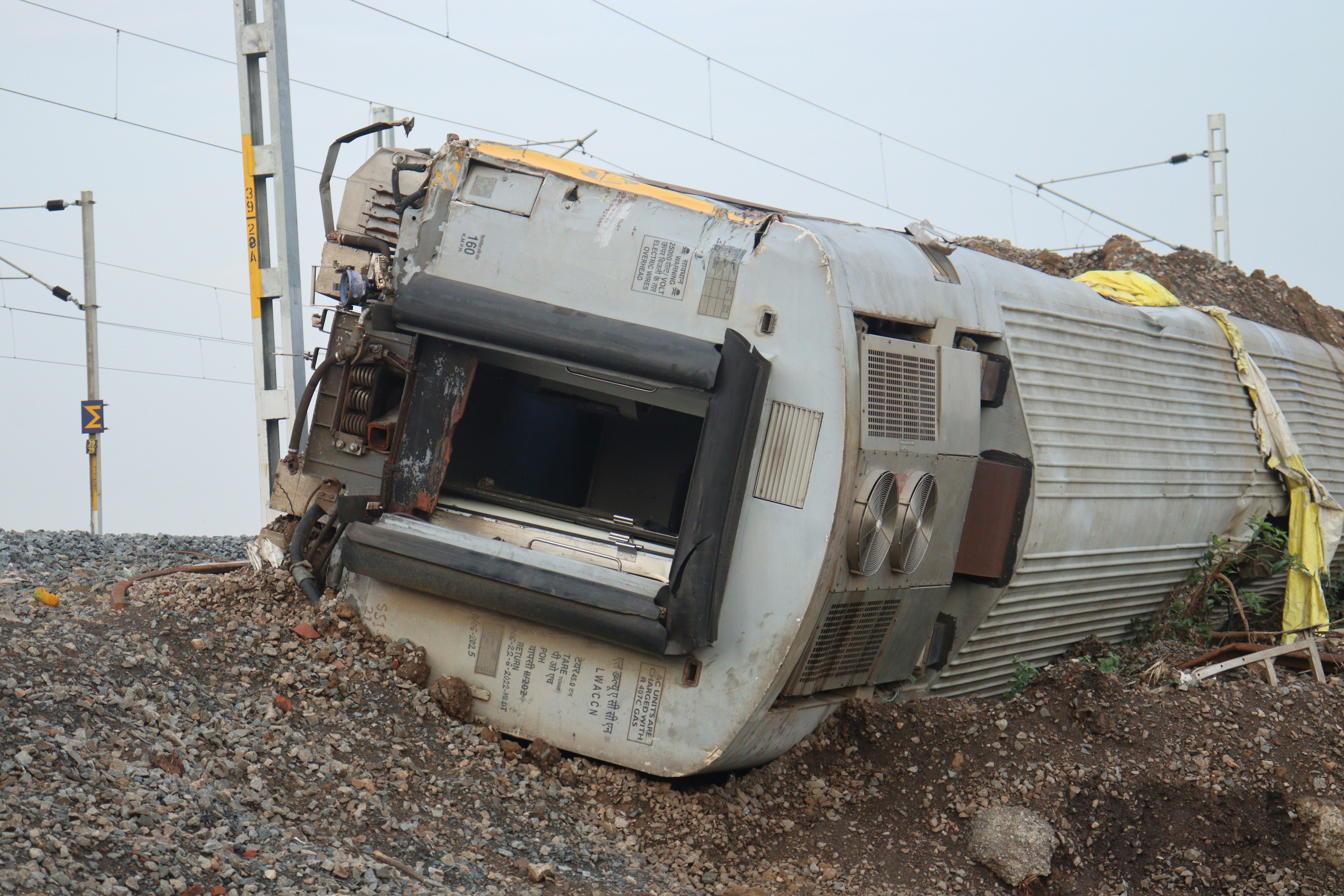 A train car lies overturned off the tracks.
