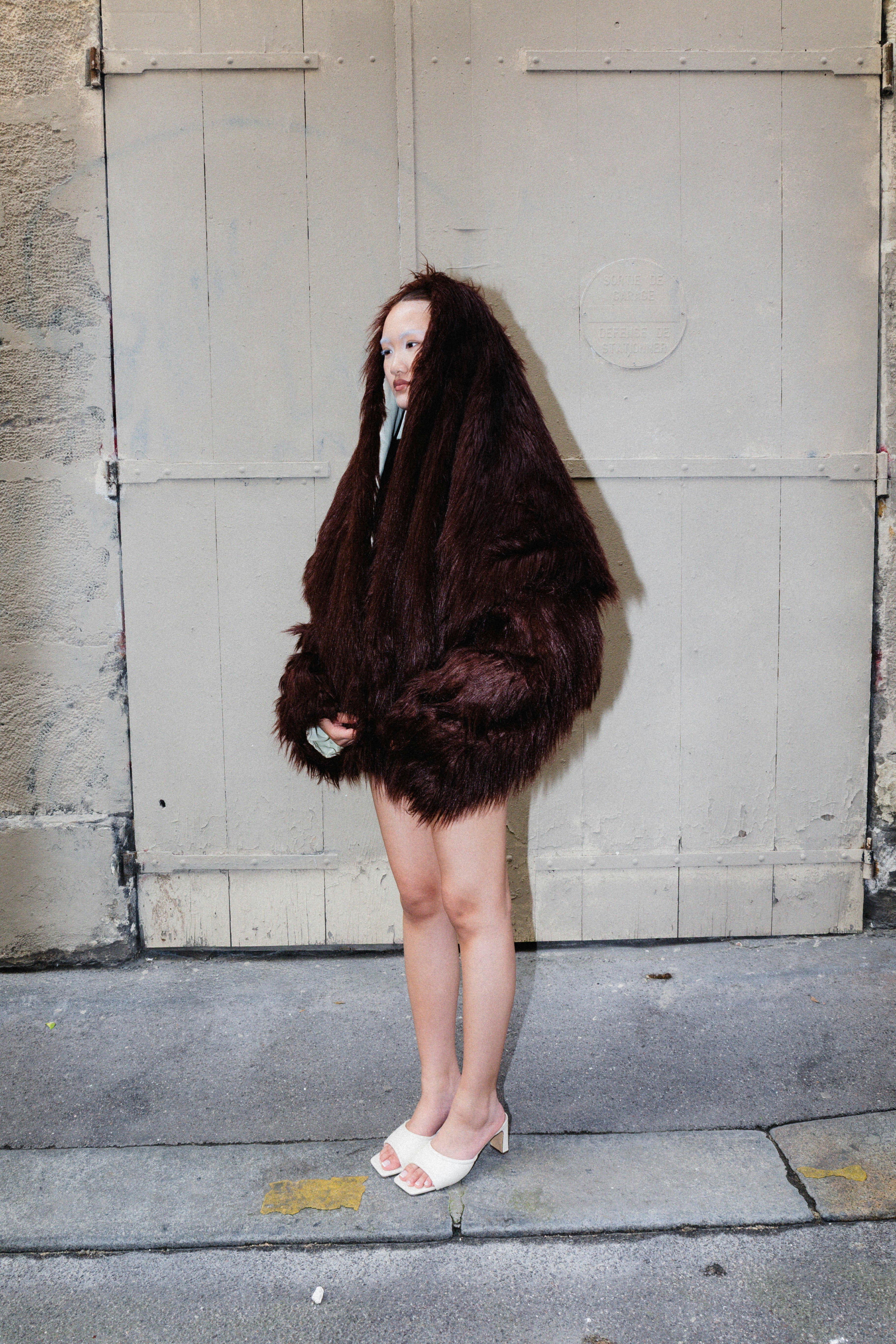 A person stands in a large furry coat.