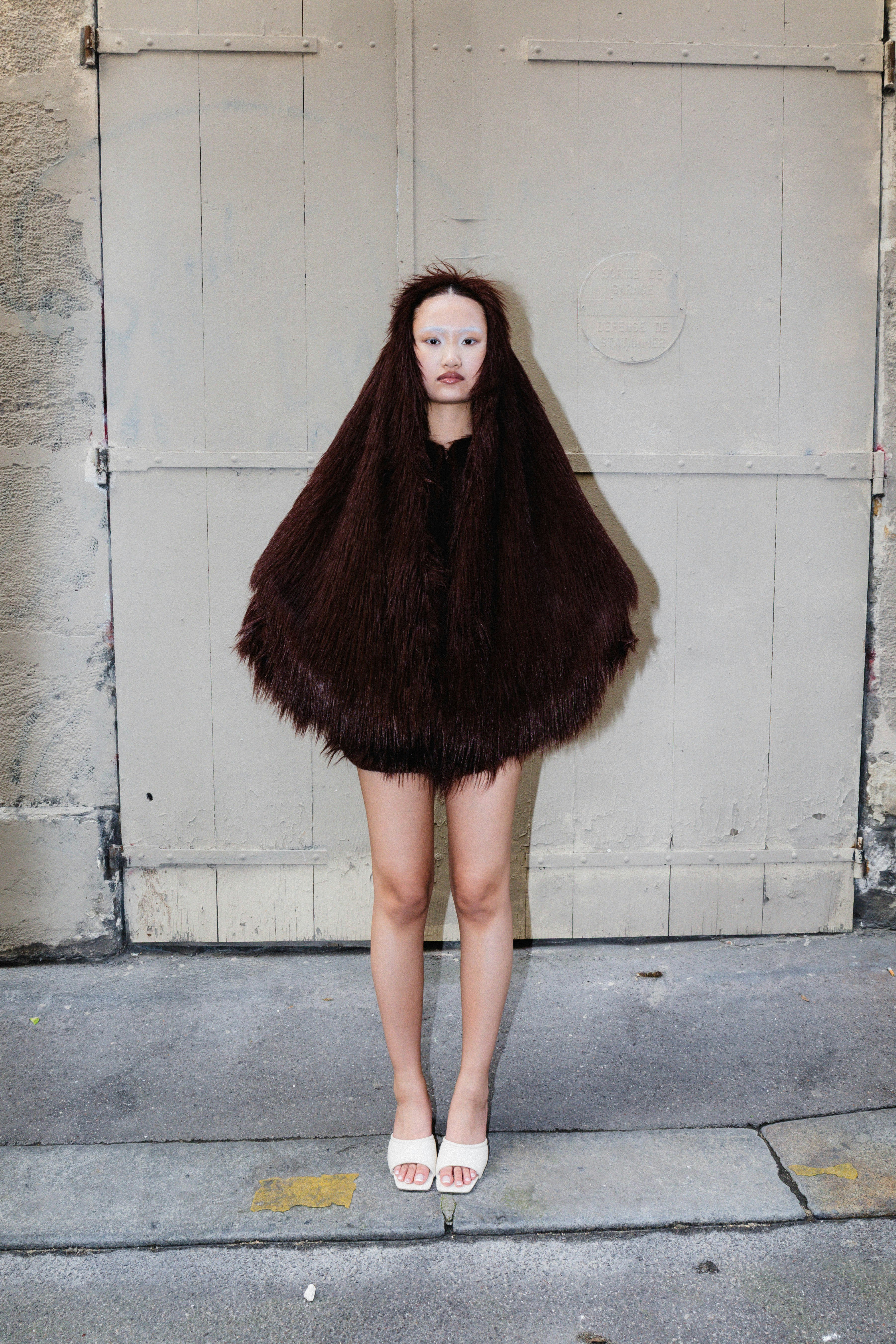 A person in a costume stands before a door.