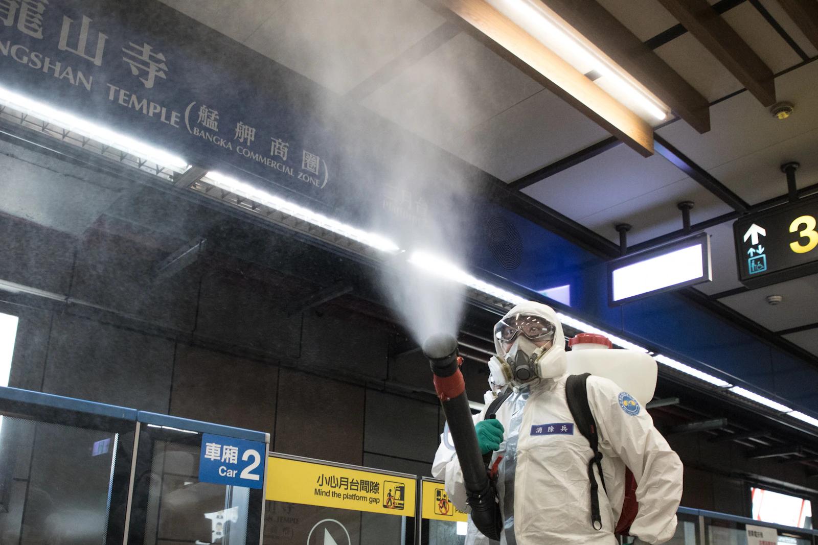 Technician in PPE sanitising a public space