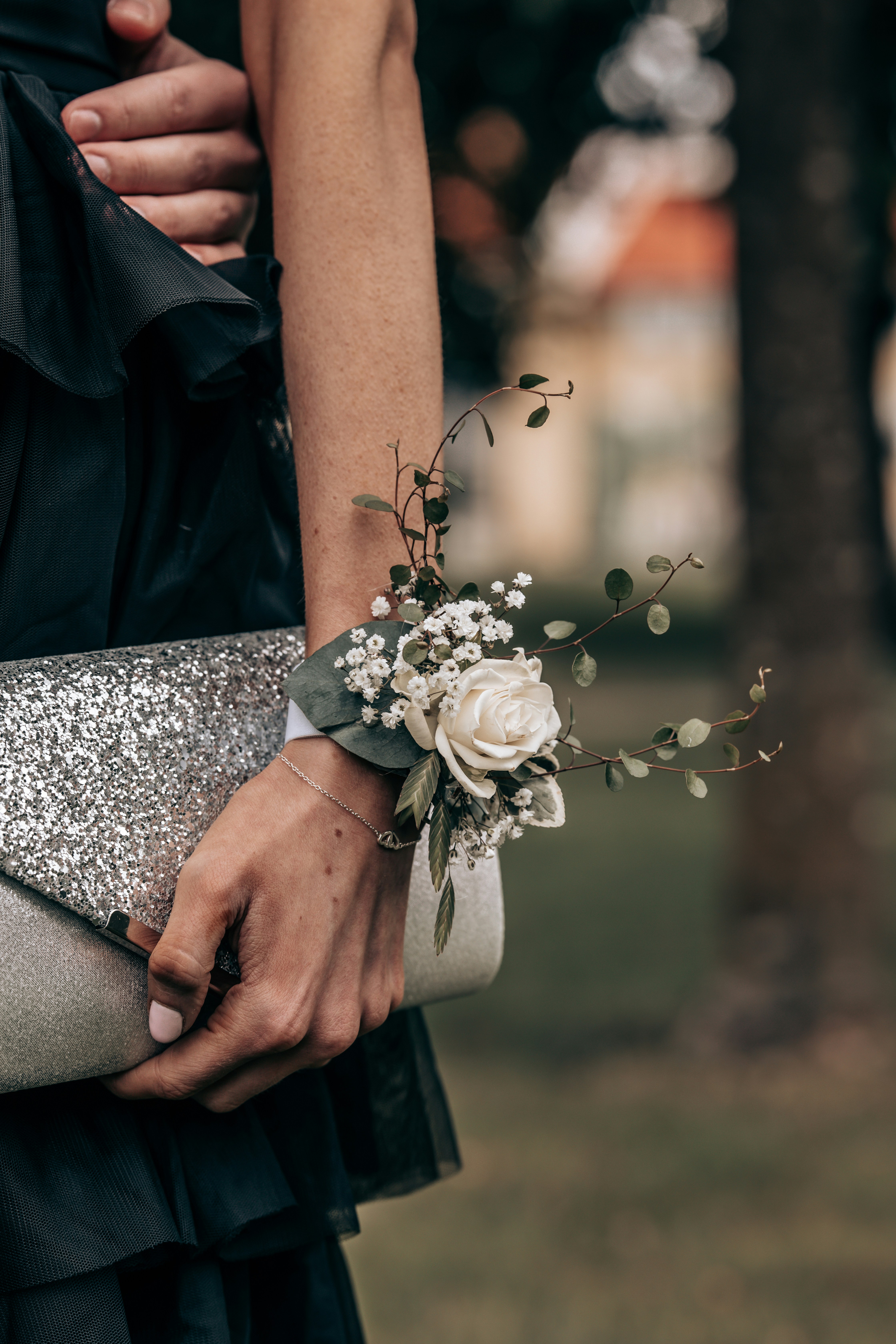 Woman holding a glitter clutch with a floral wrist corsage.