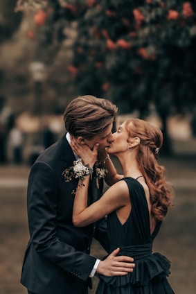 A couple shares a romantic kiss outside.
