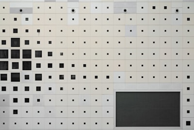 A white wall features black squares and dots.