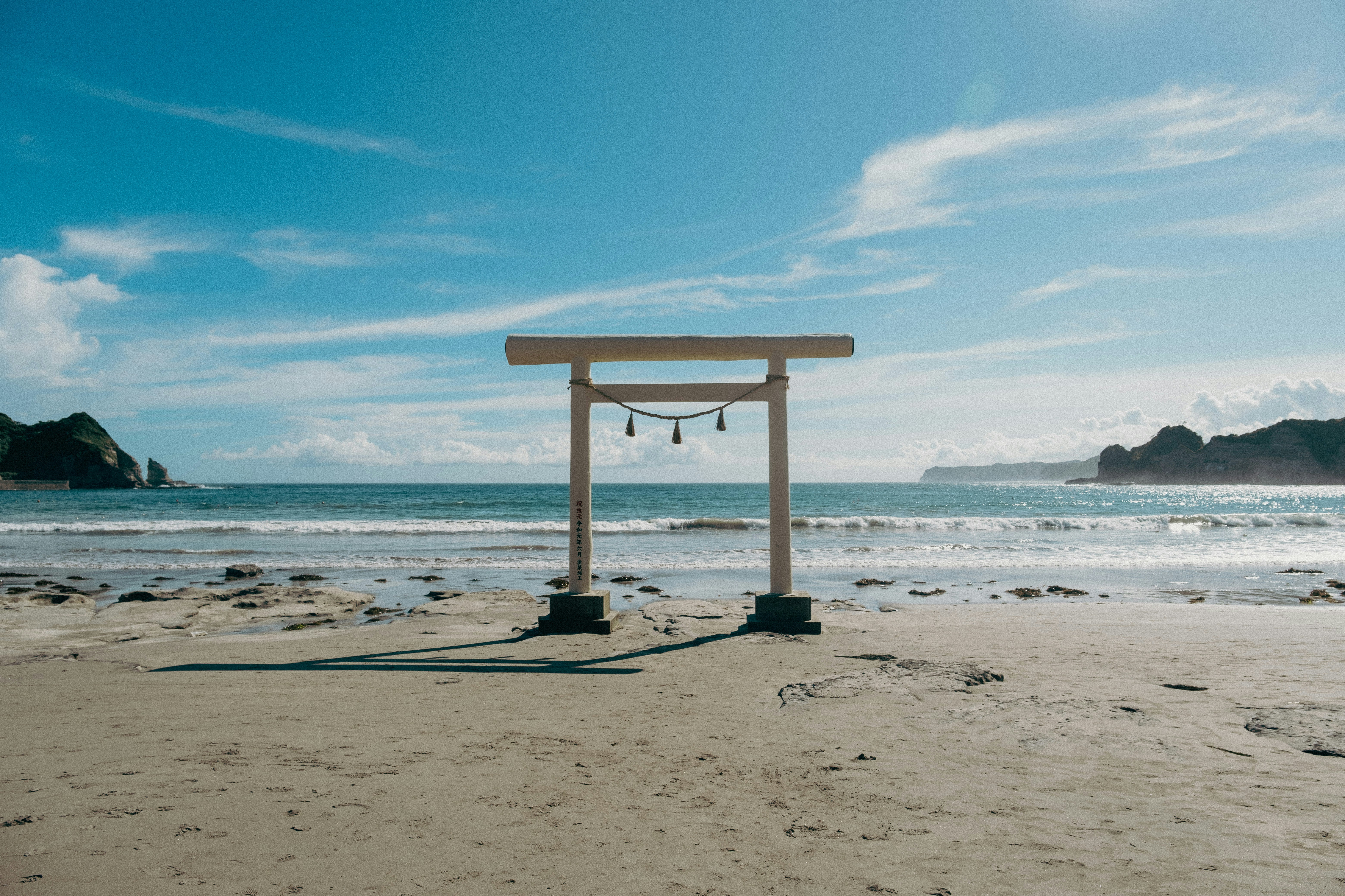 밝은 하늘 아래 해변에 나무 문이 서 있습니다.