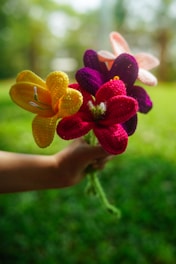 Hand holds colorful, crocheted flower bouquet.
