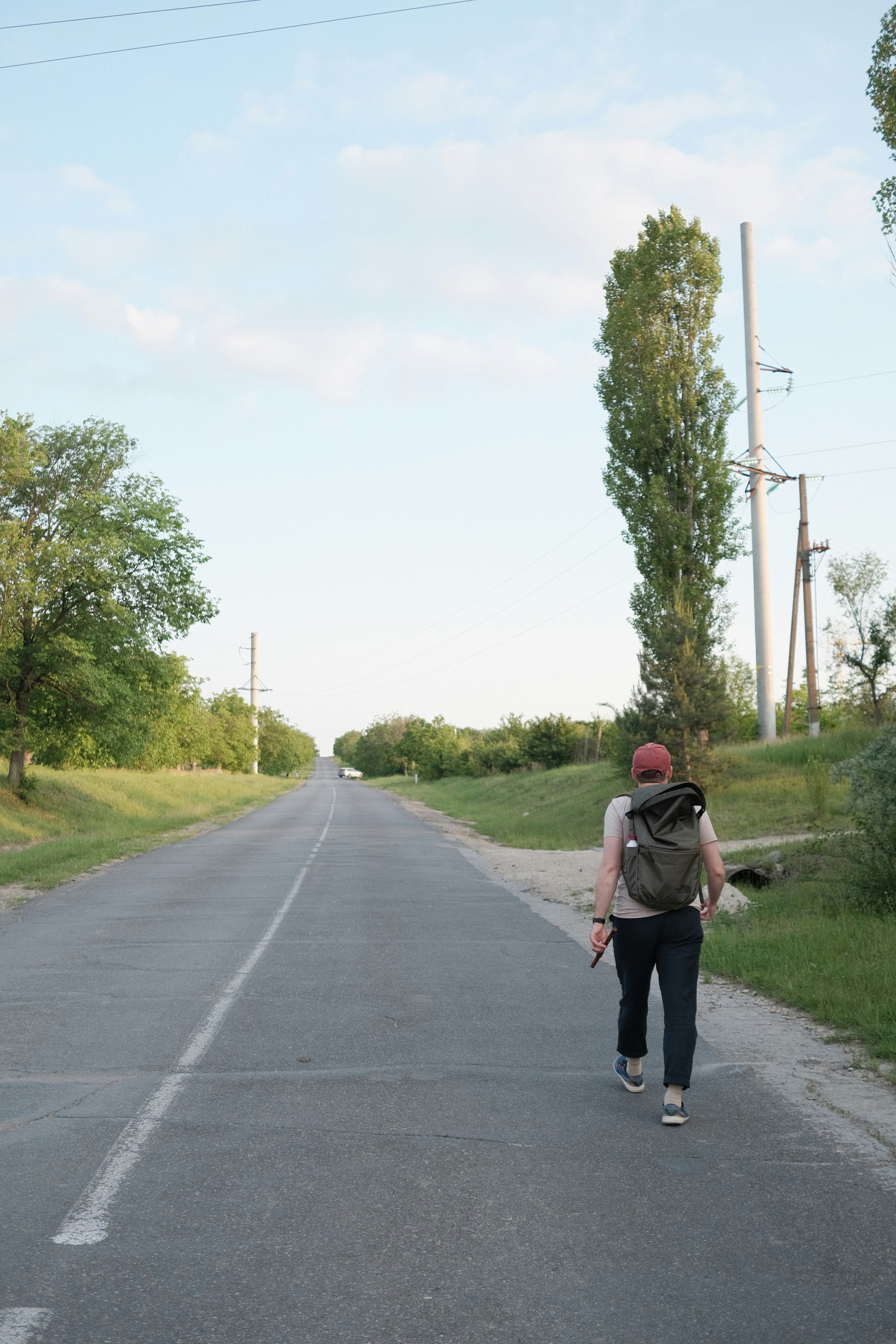 A person walks alone down a long, empty road.