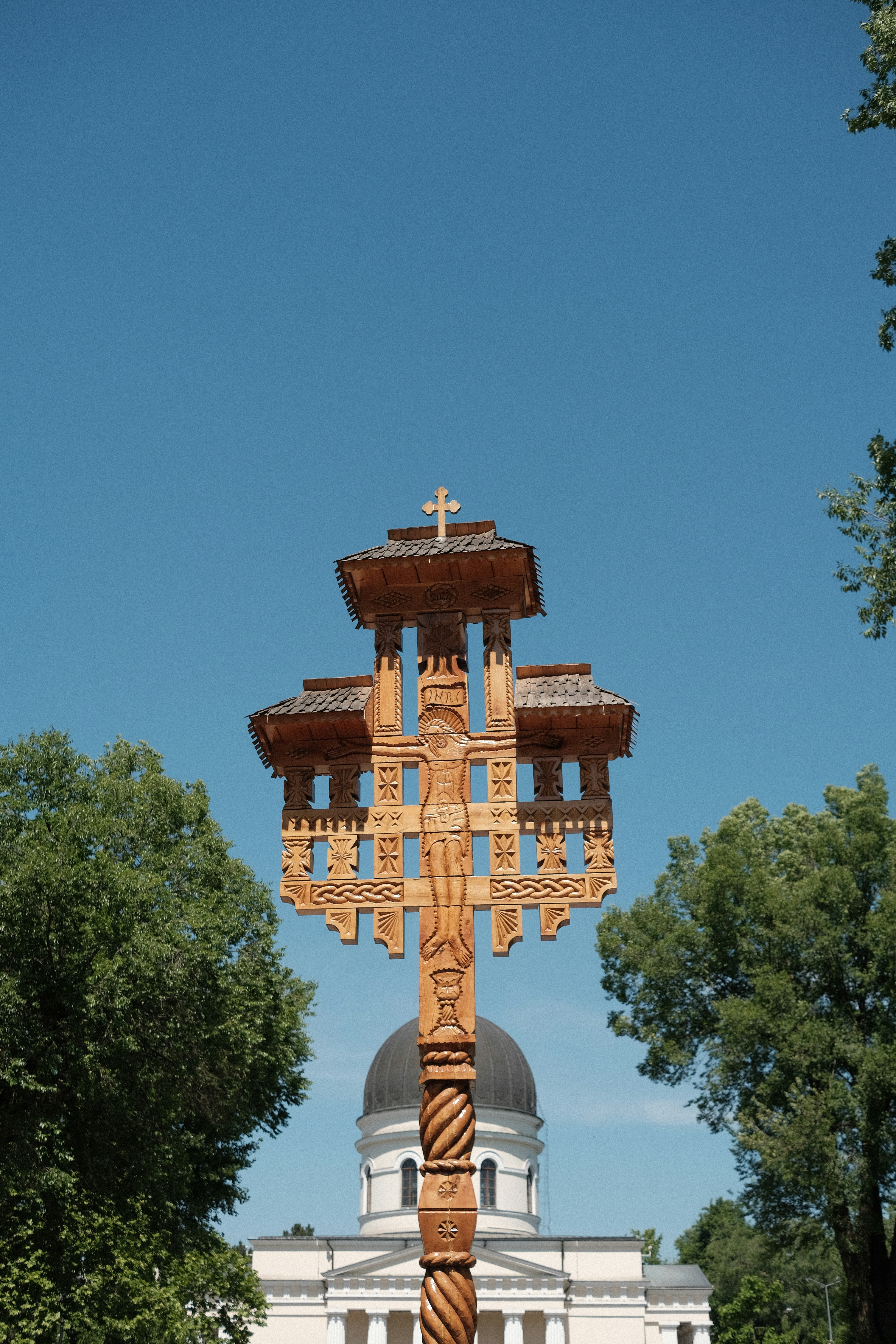 A wooden cross stands in front of a church.