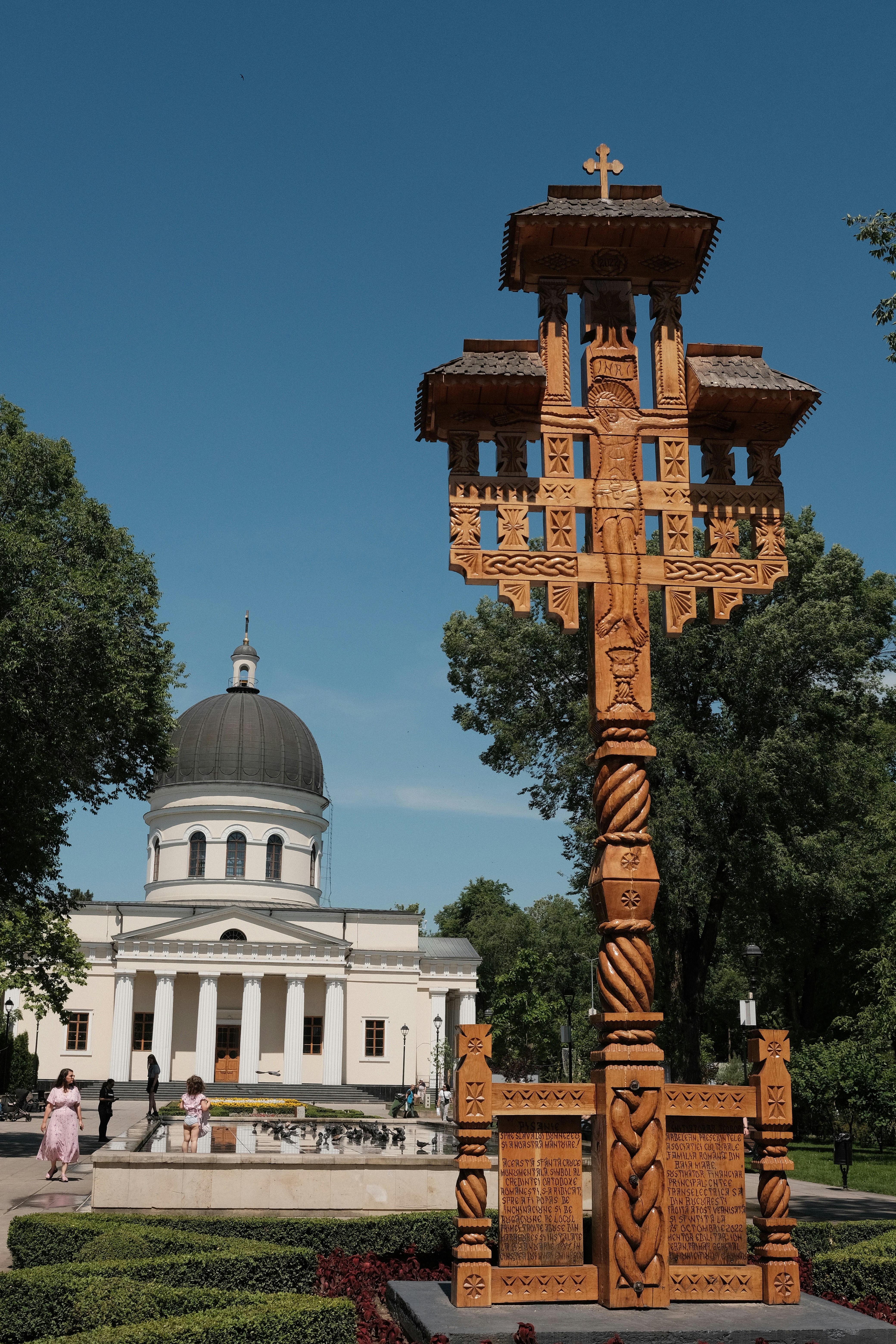 A wooden cross stands in front of a church.
