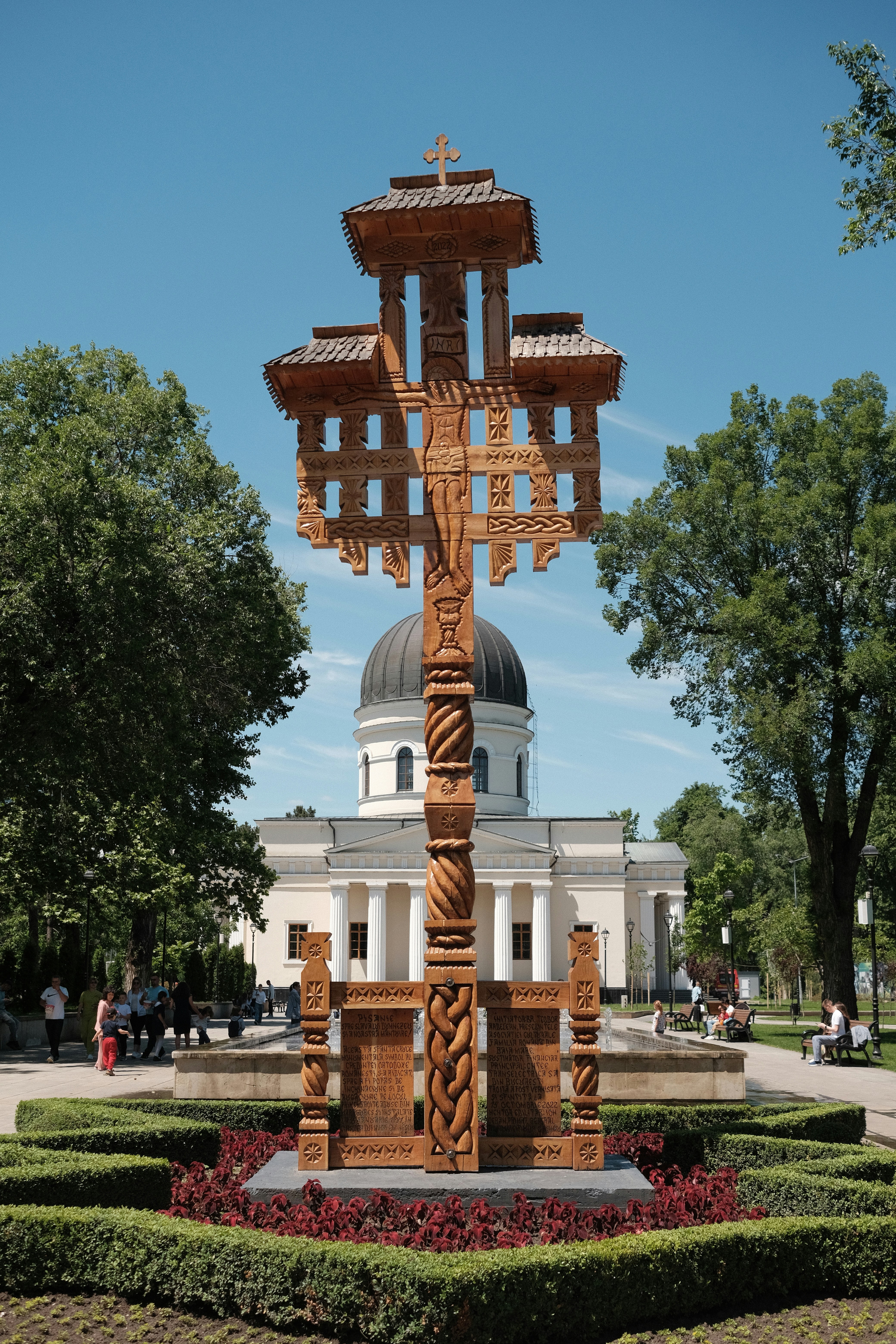 A tall wooden cross stands in front of a church.