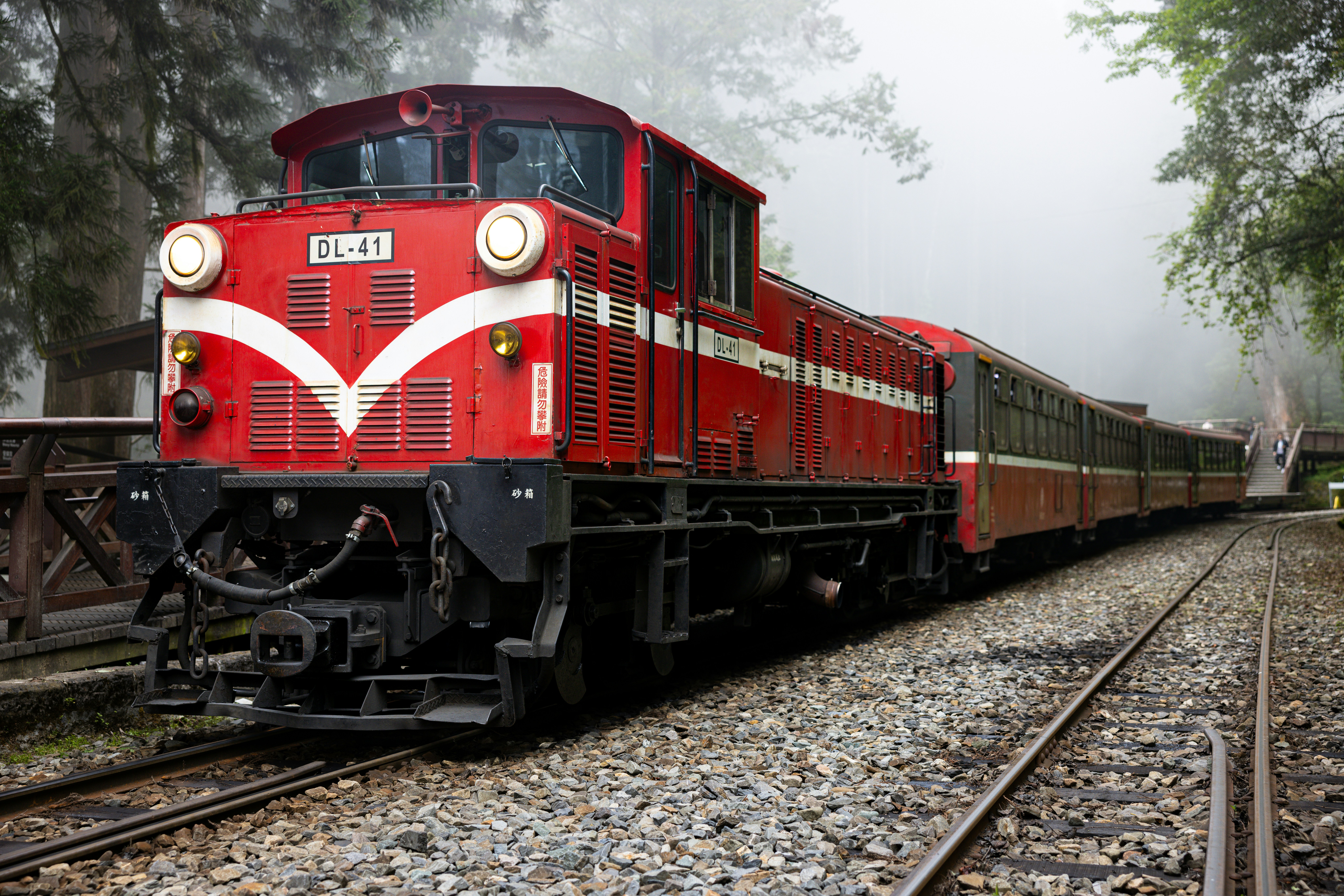 Un train rouge circule le long des voies.