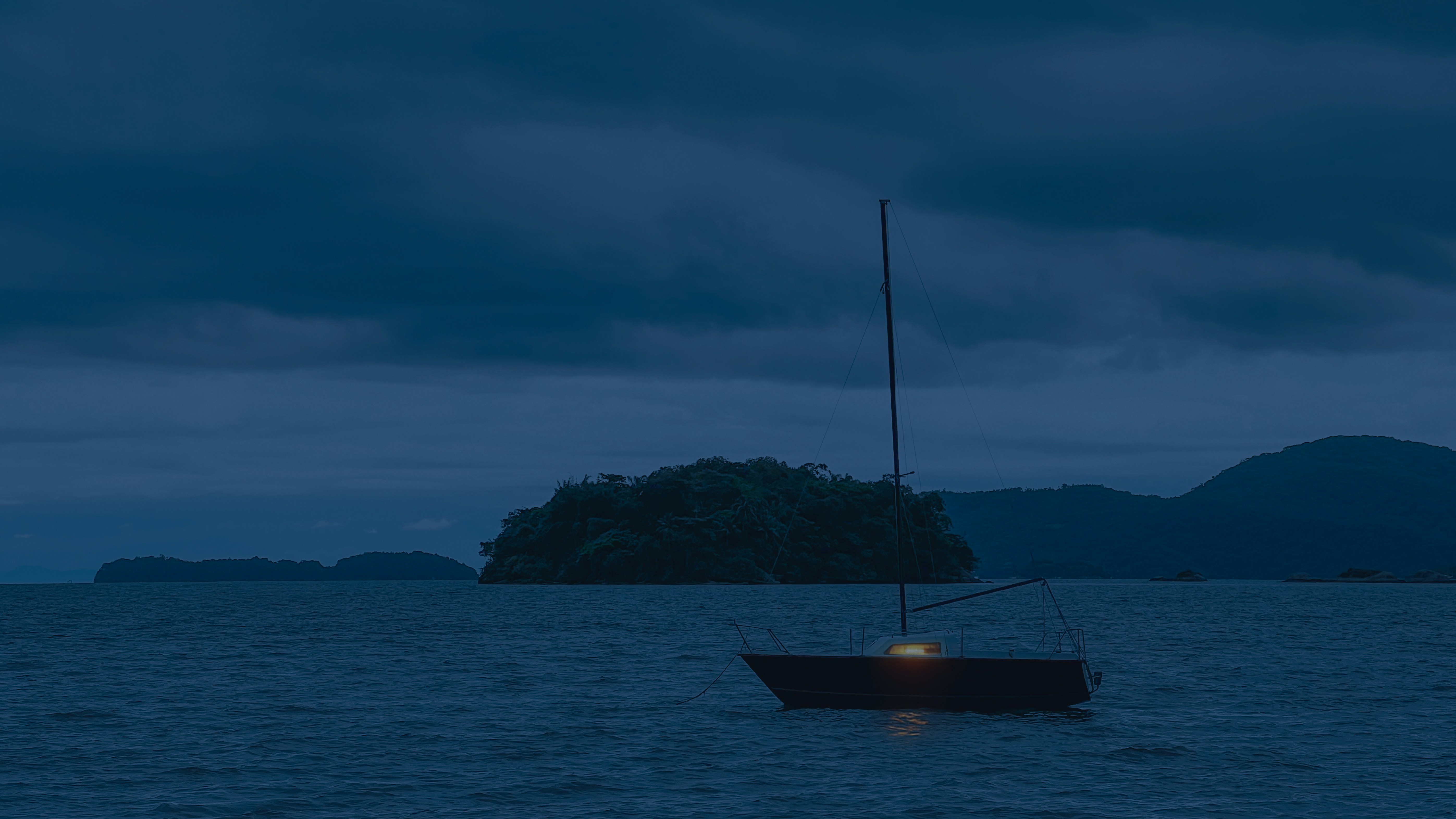 A solitary sailboat sits on the water at dusk.