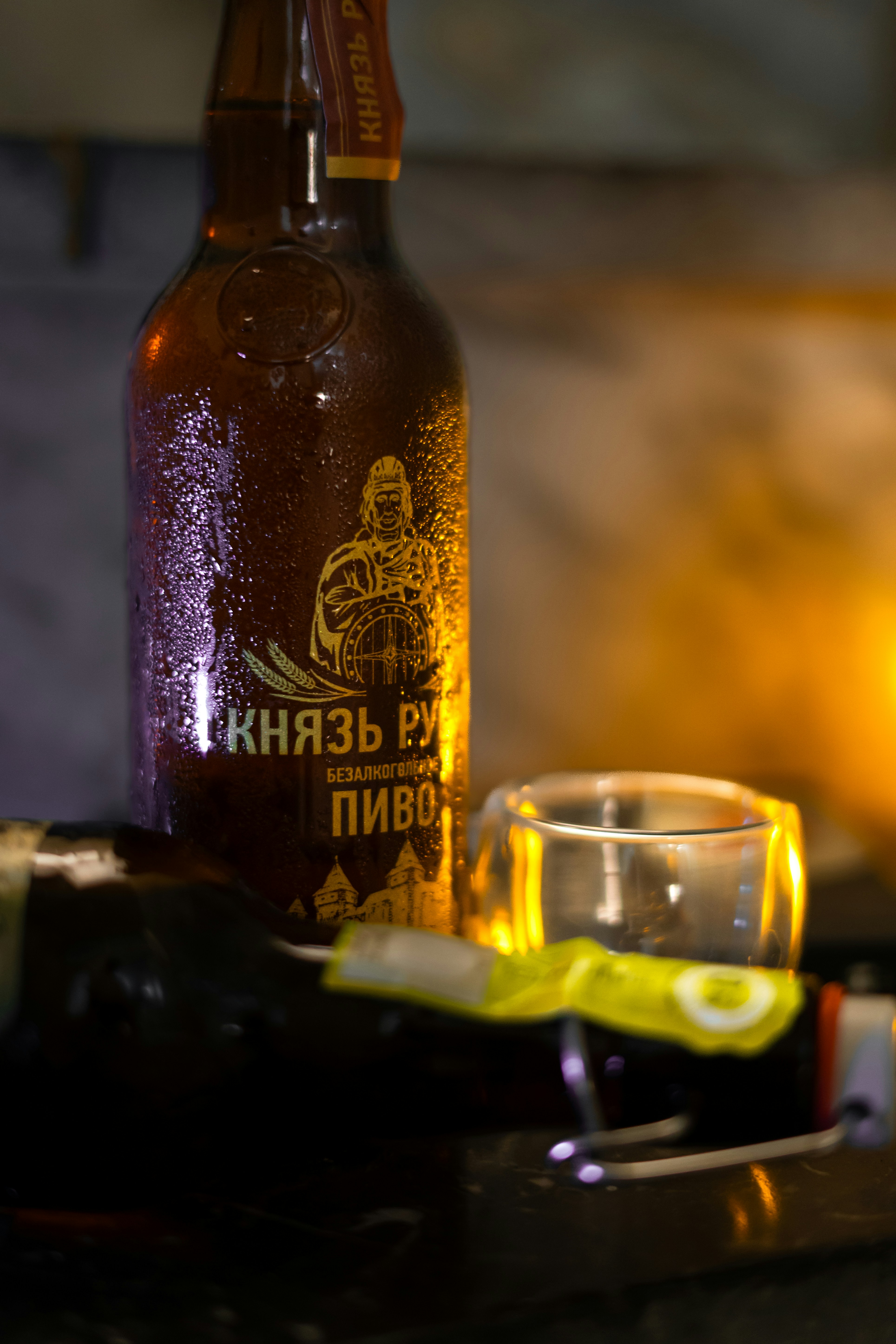 A bottle of beer sits near an empty glass.