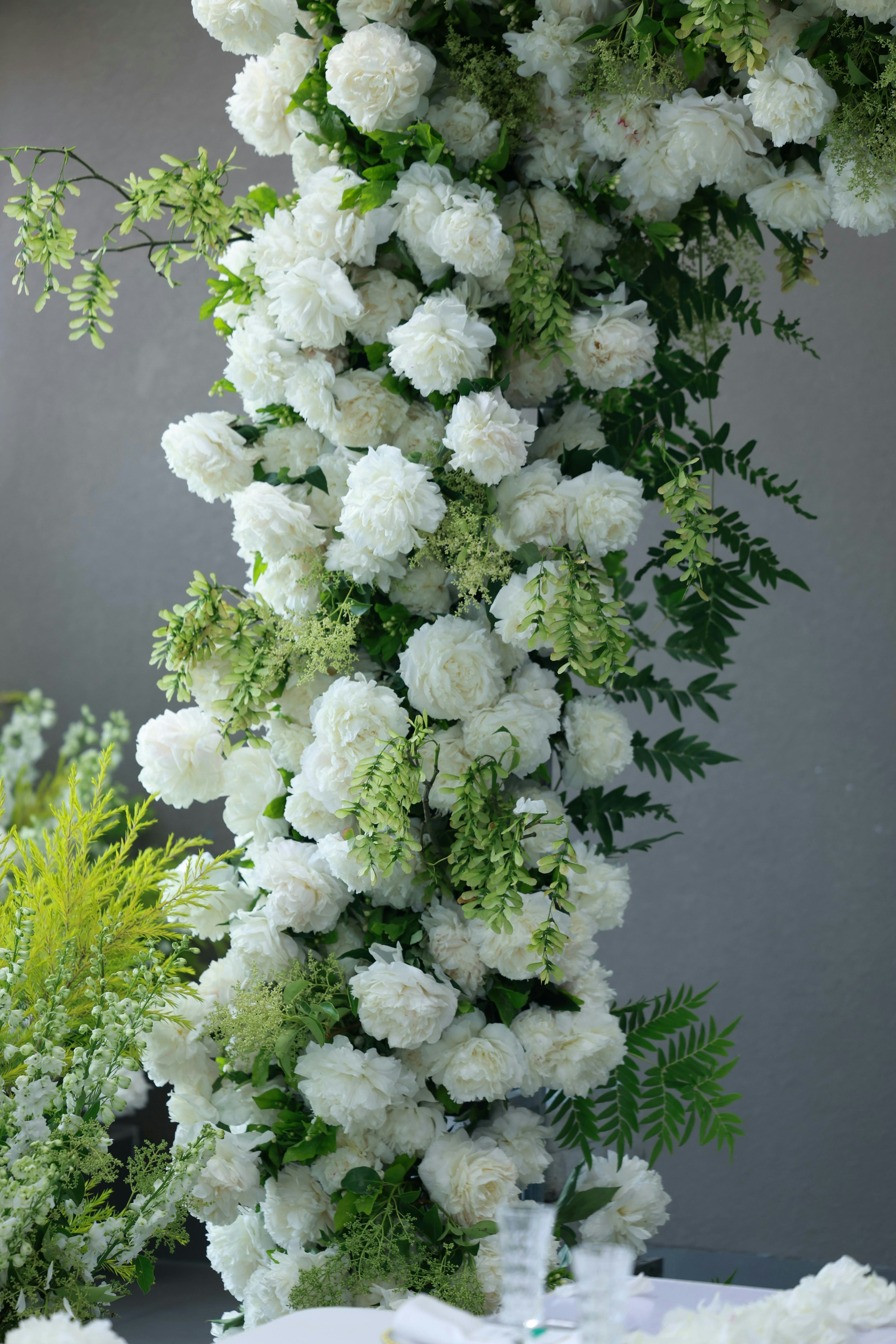 Detail of a dense white faux floral arrangement with greenery