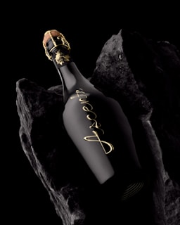 A black bottle of liquor on rocks.
