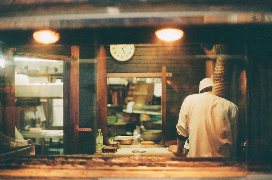A chef plating at the pass of a dim restaurant kitchen