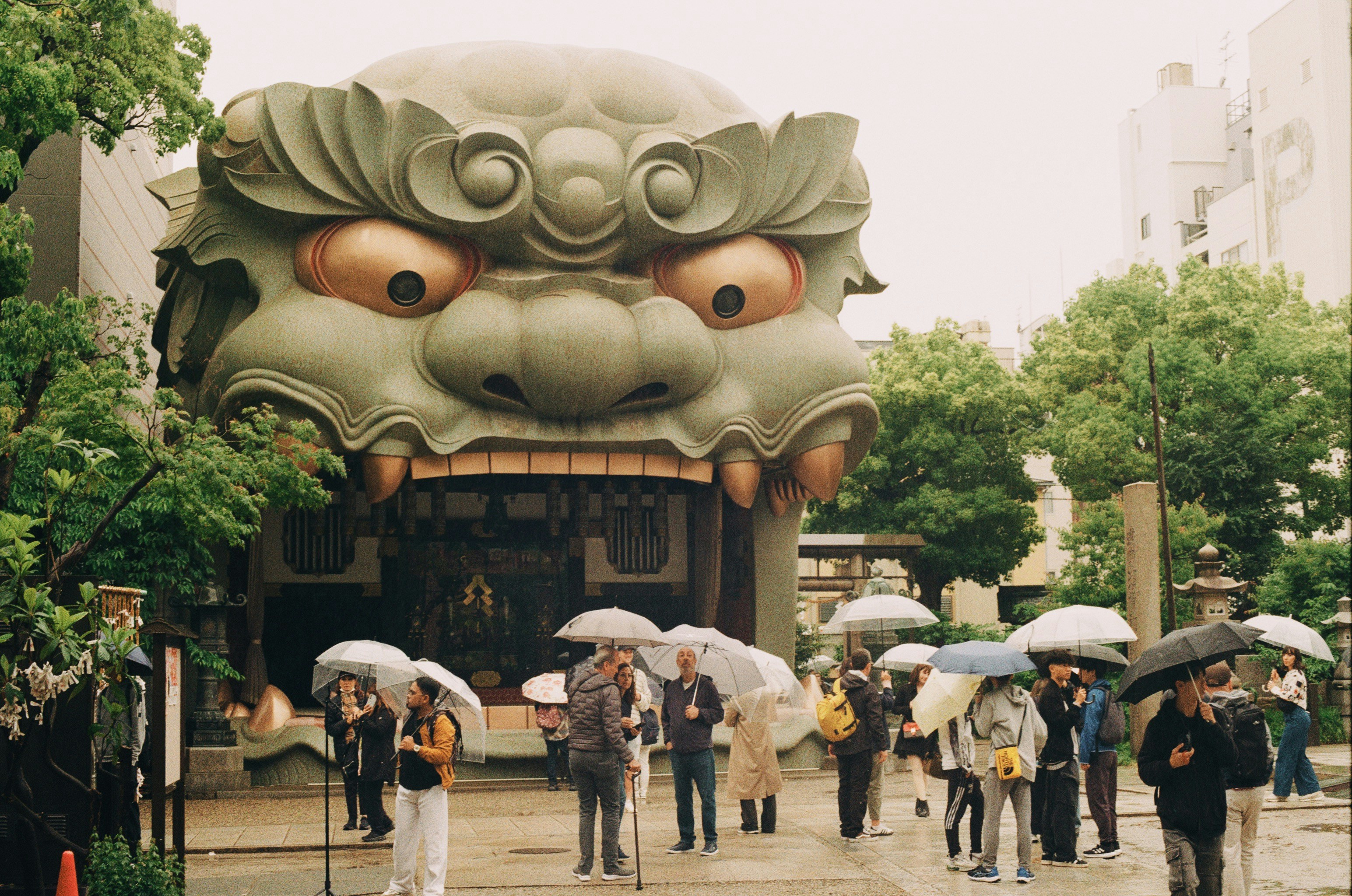 Giant creature's head over temple with people.