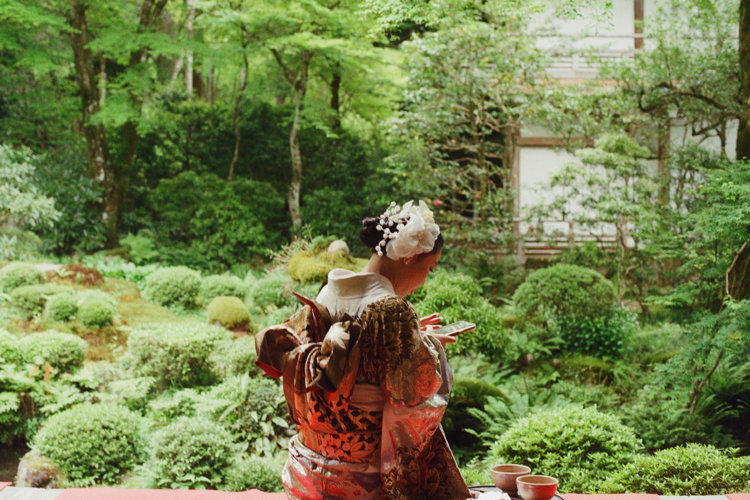A woman in kimono enjoys a garden view.