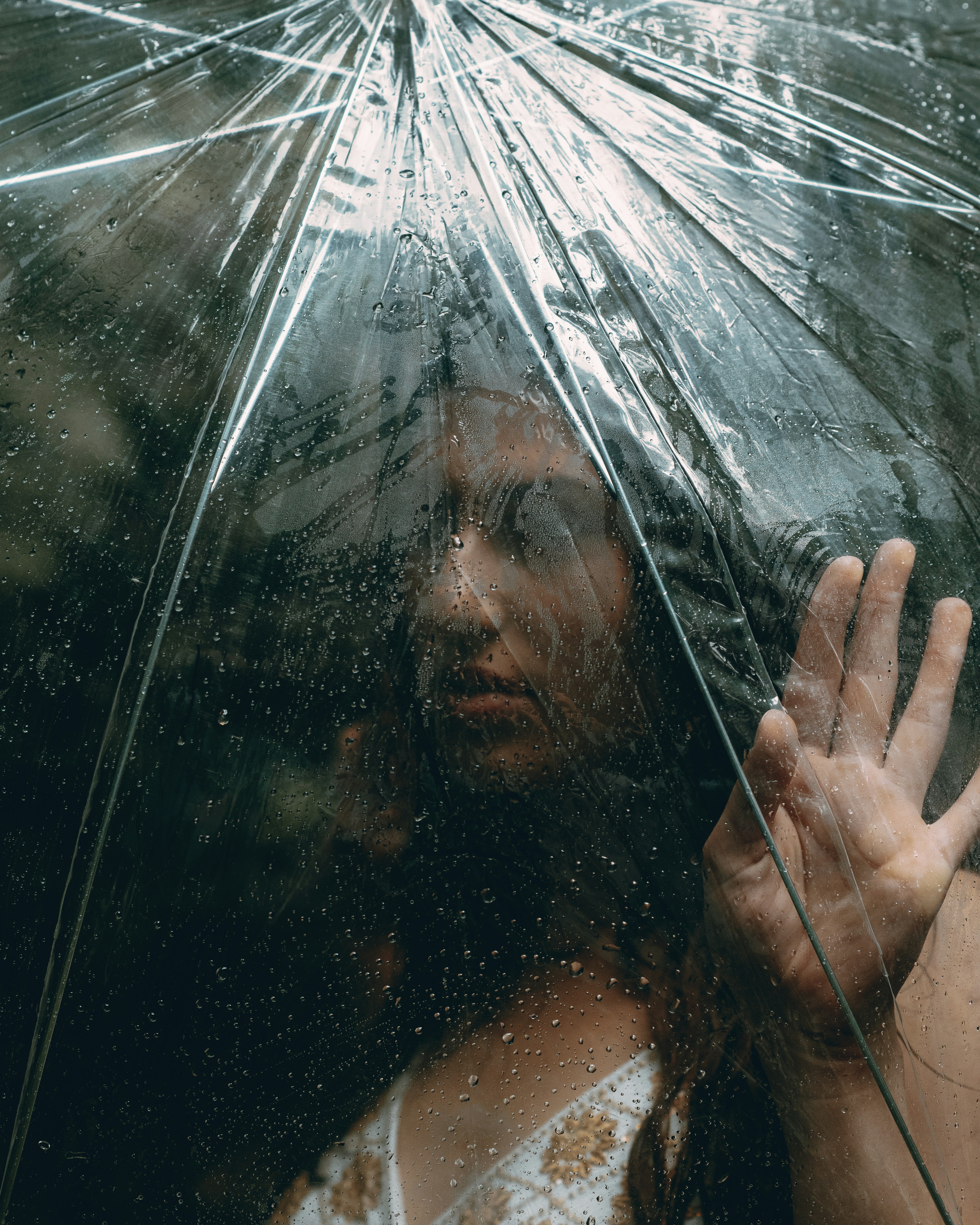 Eine Frau berührt den Regen durch einen Regenschirm.