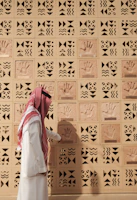 A man examines handprints on a patterned wall.