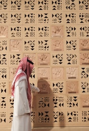 A man examines handprints on a patterned wall.