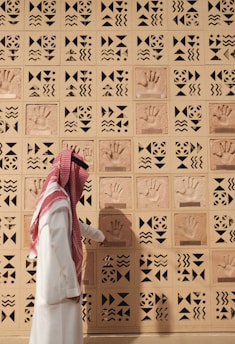 A man examines handprints on a patterned wall.