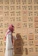 A man examines handprints on a patterned wall.