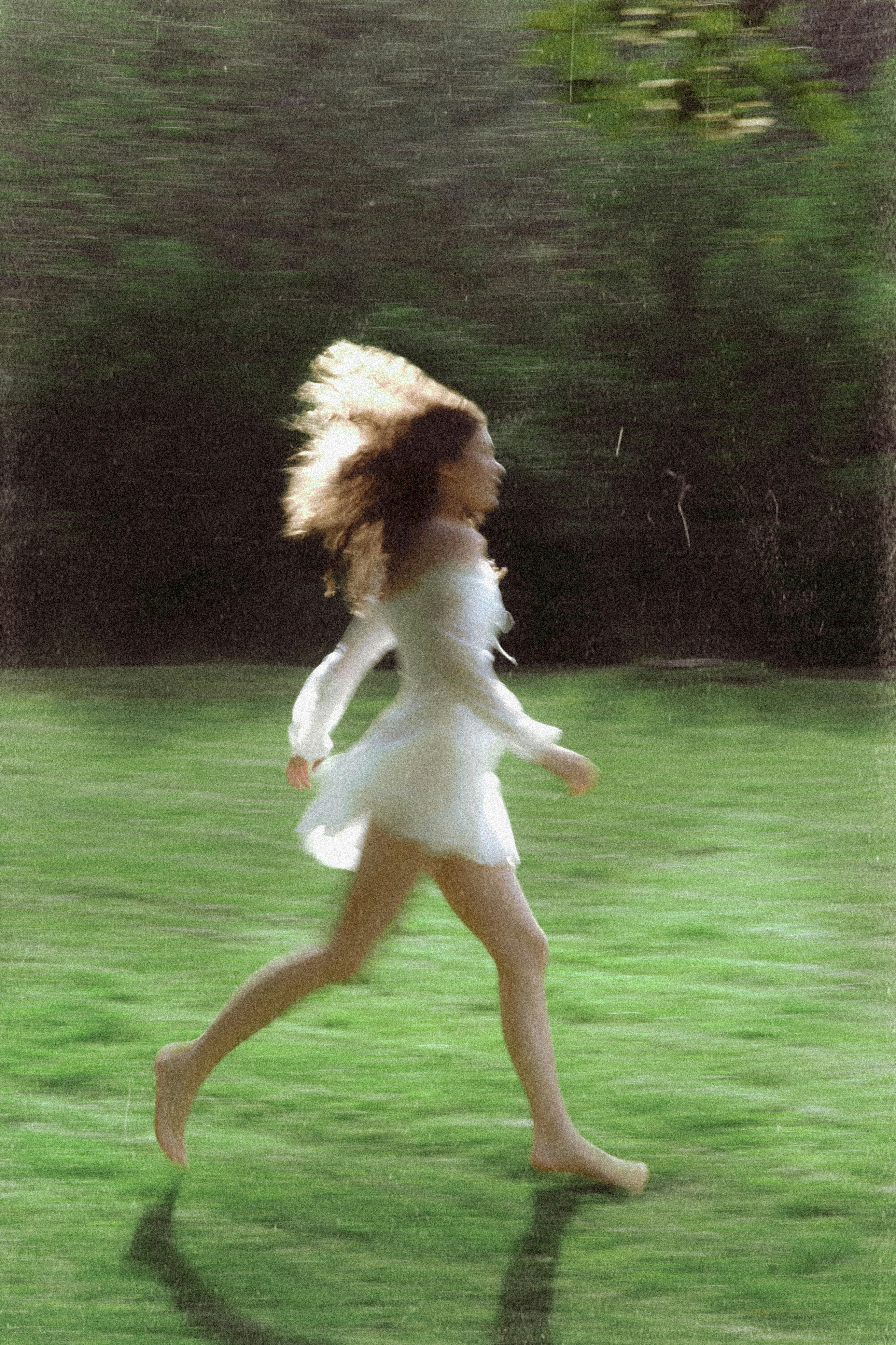 Uma mulher corre descalça por um campo verde.