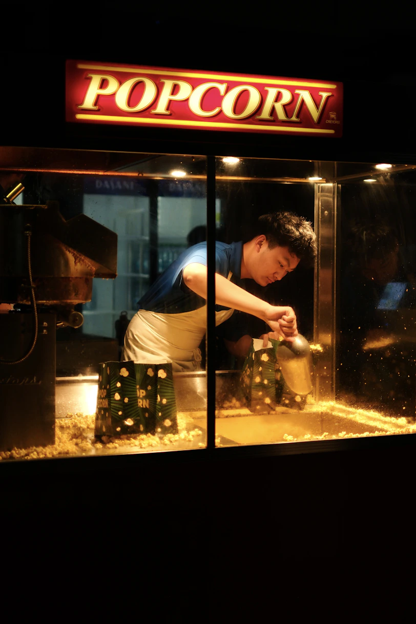A person scoops popcorn from a vending machine.