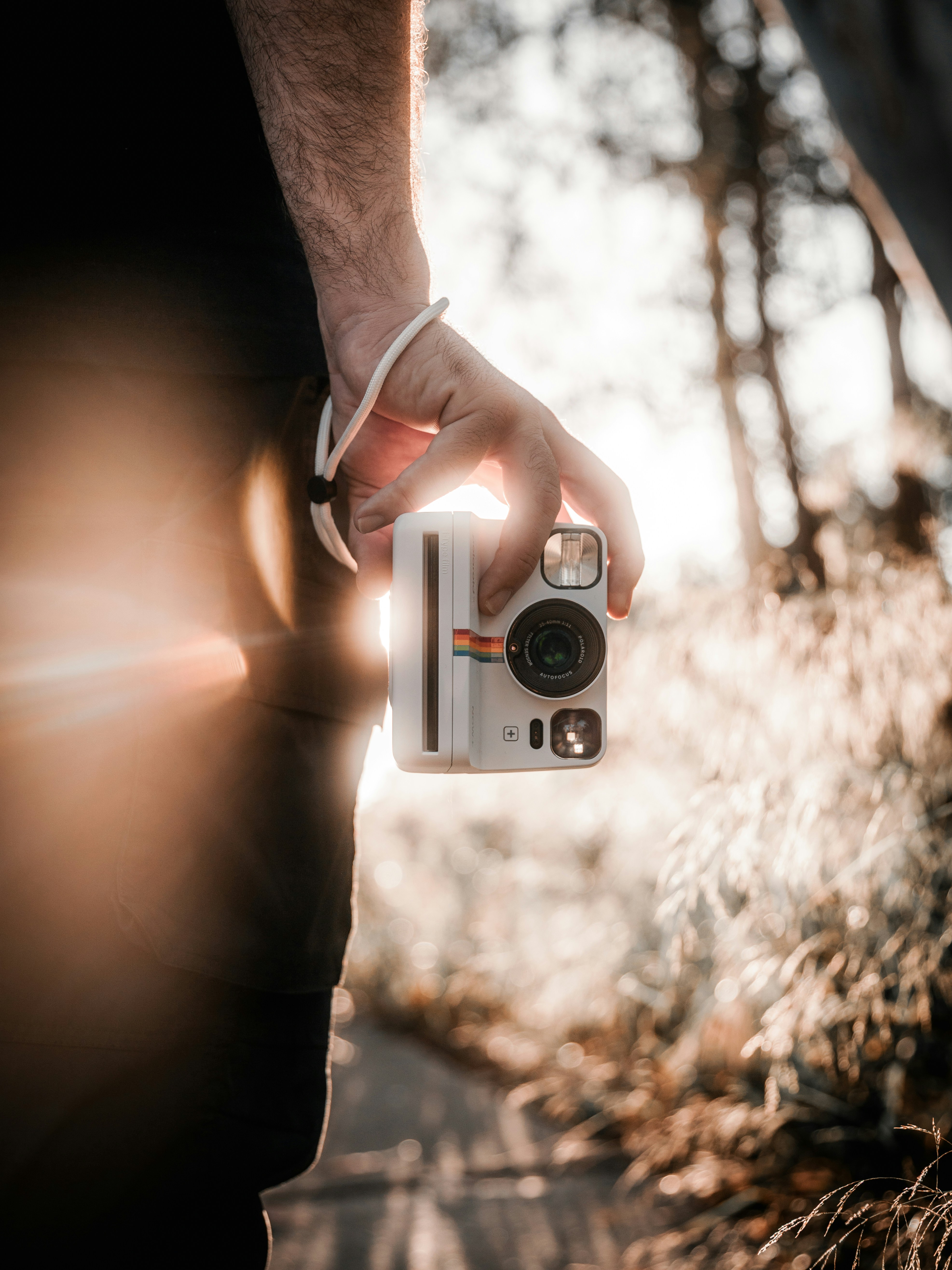 A person holds a polaroid camera in the sun.