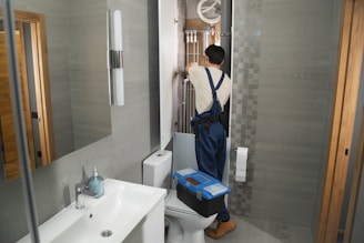 A plumber repairs plumbing in a bathroom.