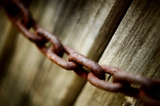 A rusty chain rests against wood.
