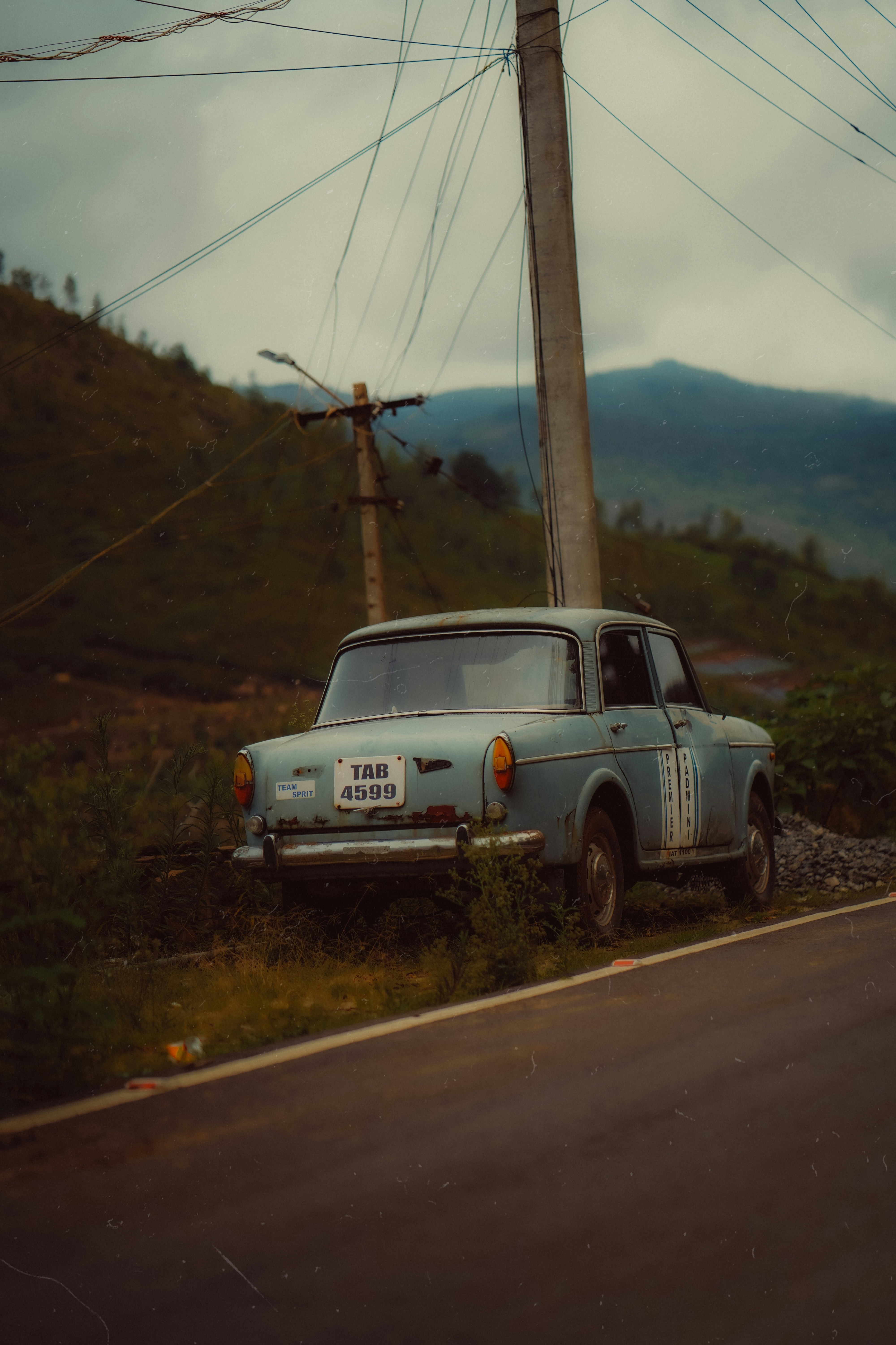 An old car is parked near a road