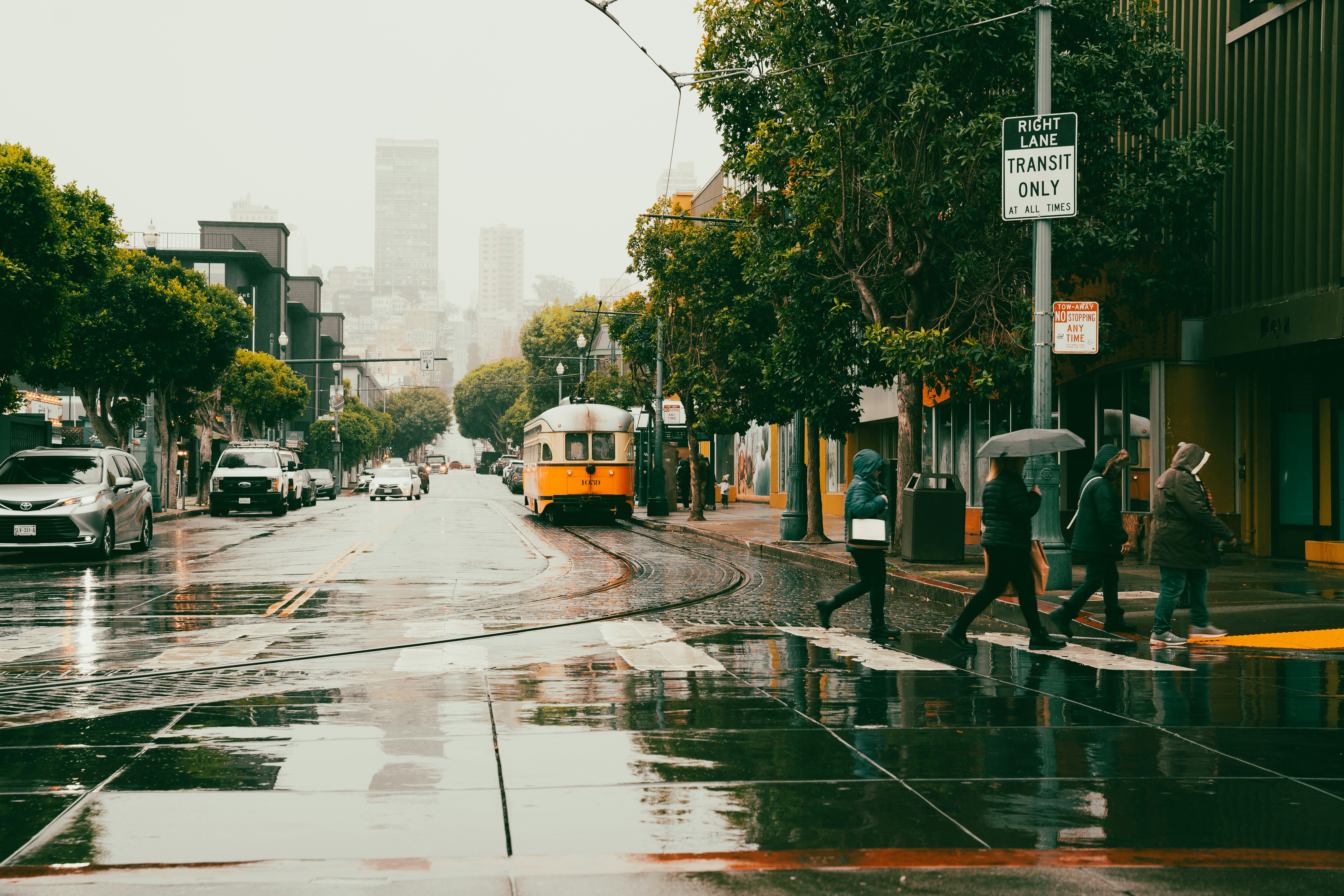 People cross a street in a rainy city.