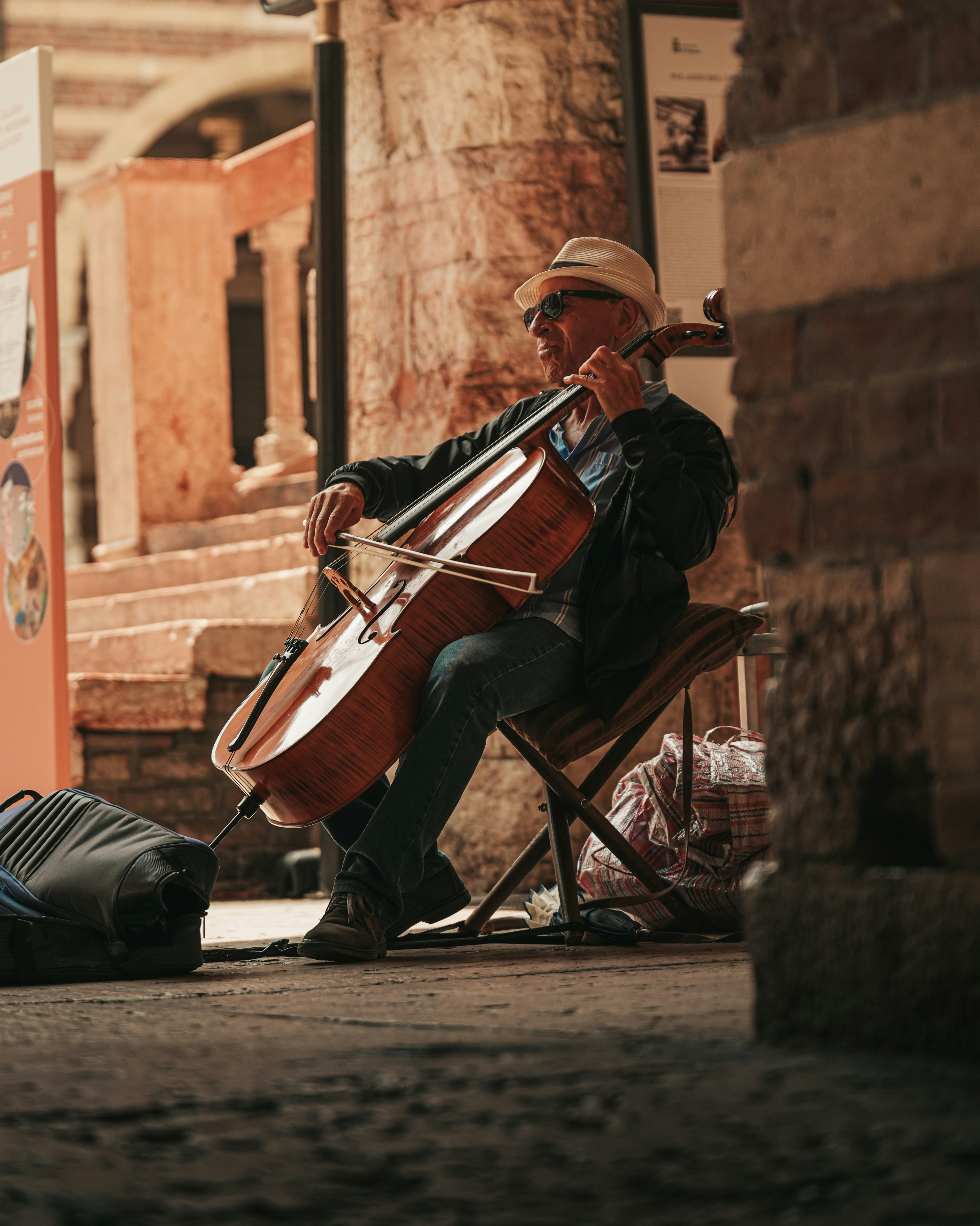 A cellist plays in a stone archway.