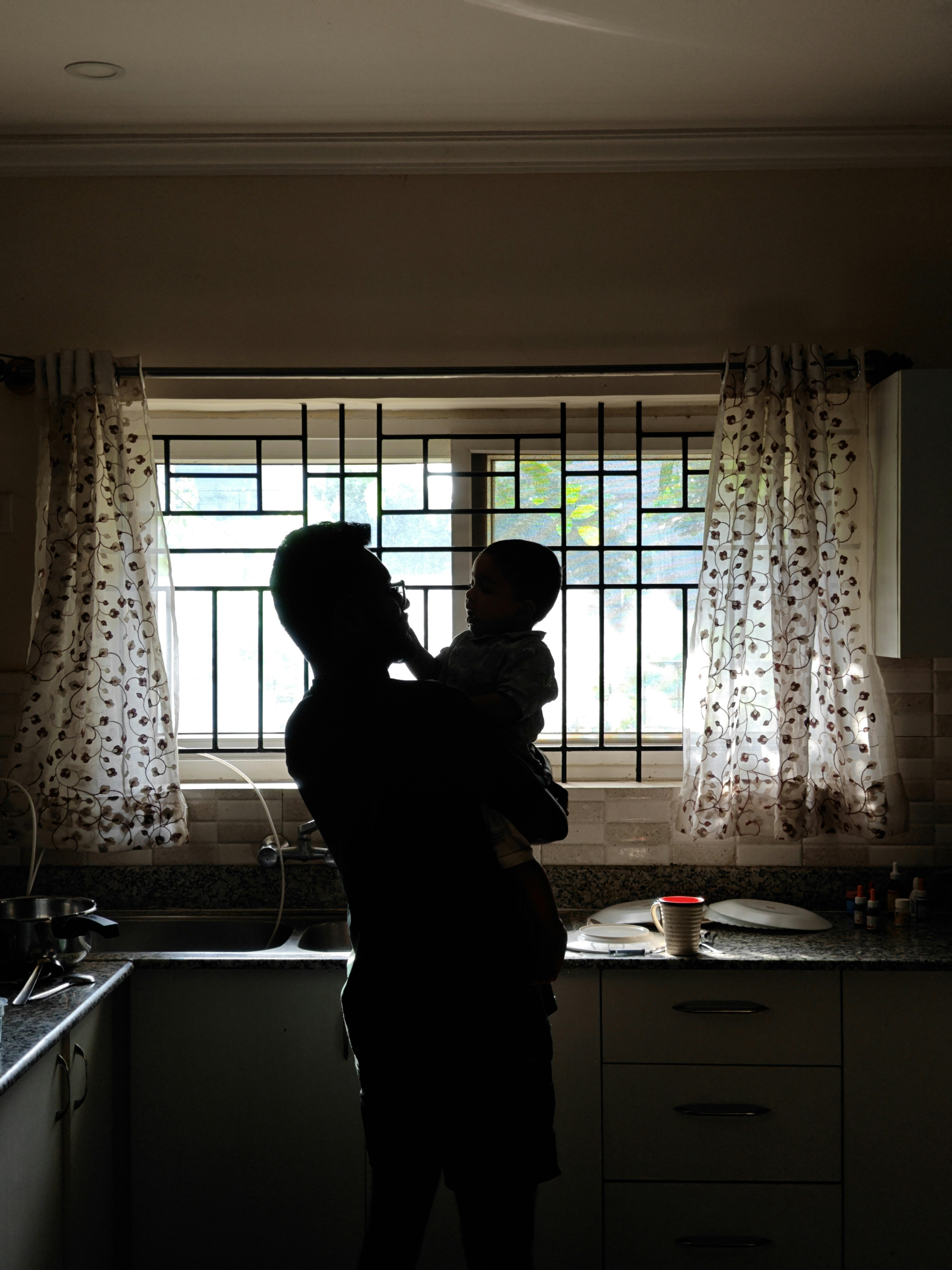 Vater hält Baby in der Küchensilhouette.