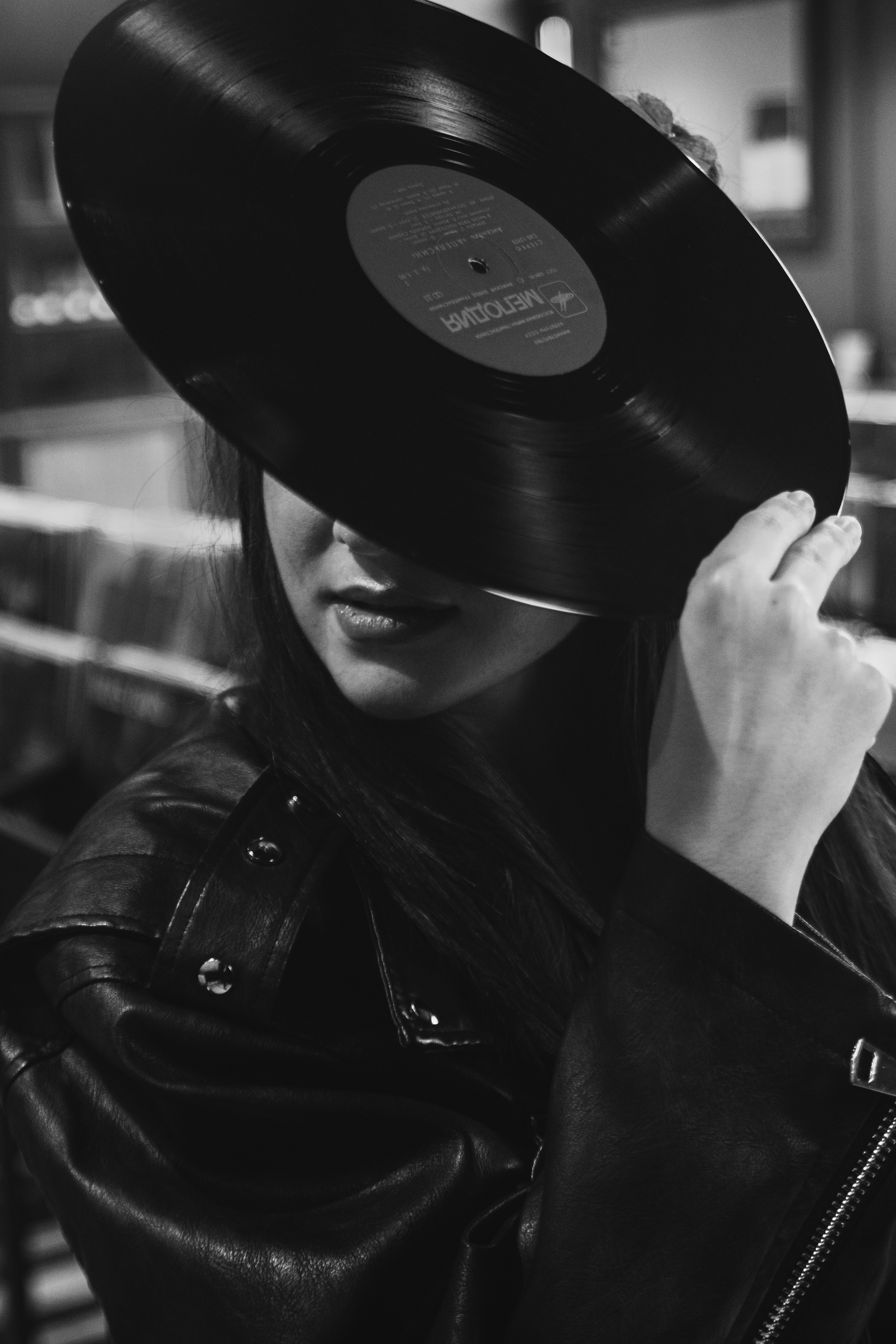 Une femme tient un disque vinyle devant son visage.