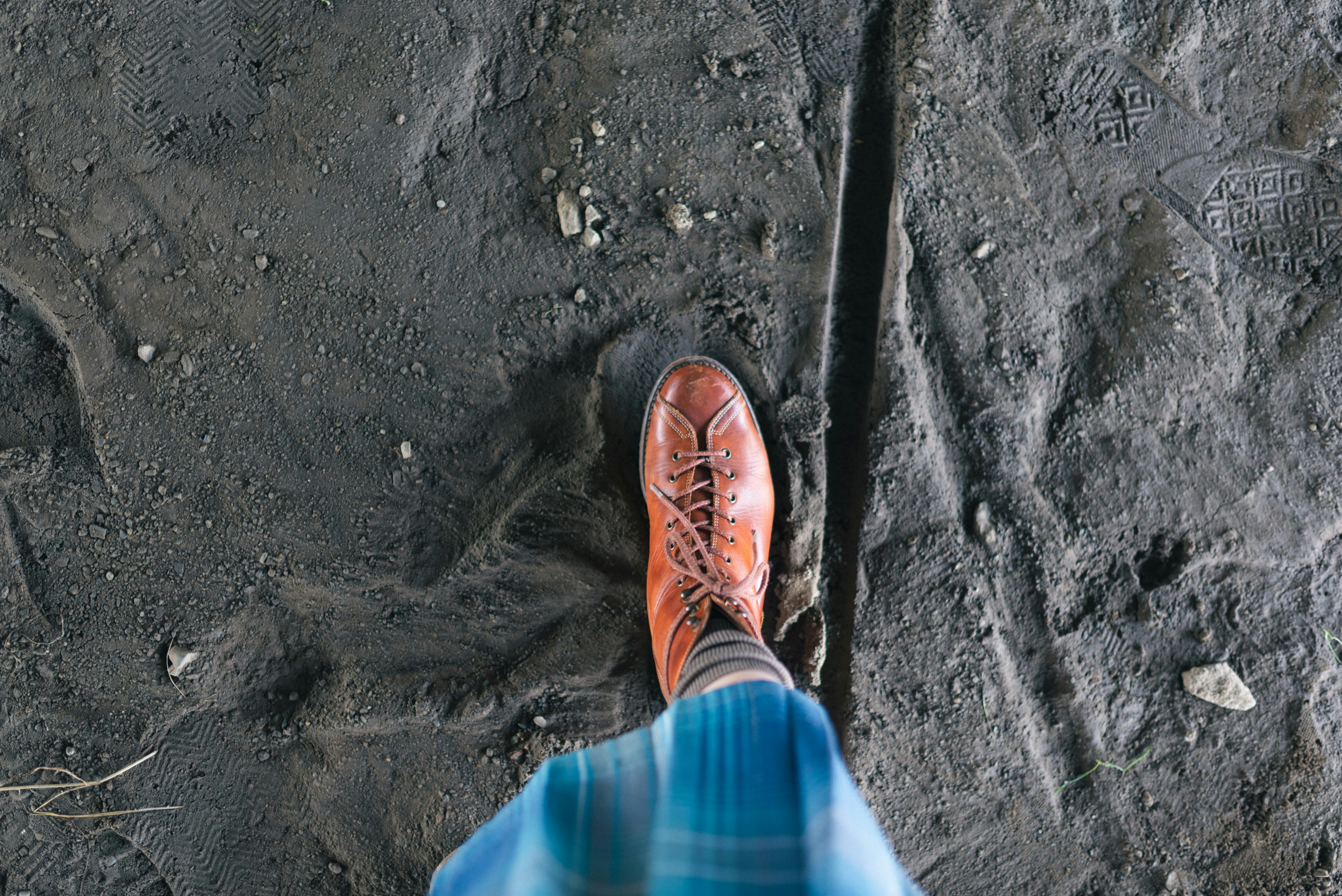 Foot with orange shoe walking on mud.