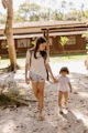 Two young girls hold hands and walk together.