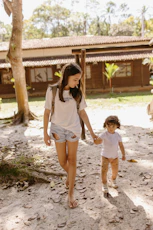 Two young girls hold hands and walk together.