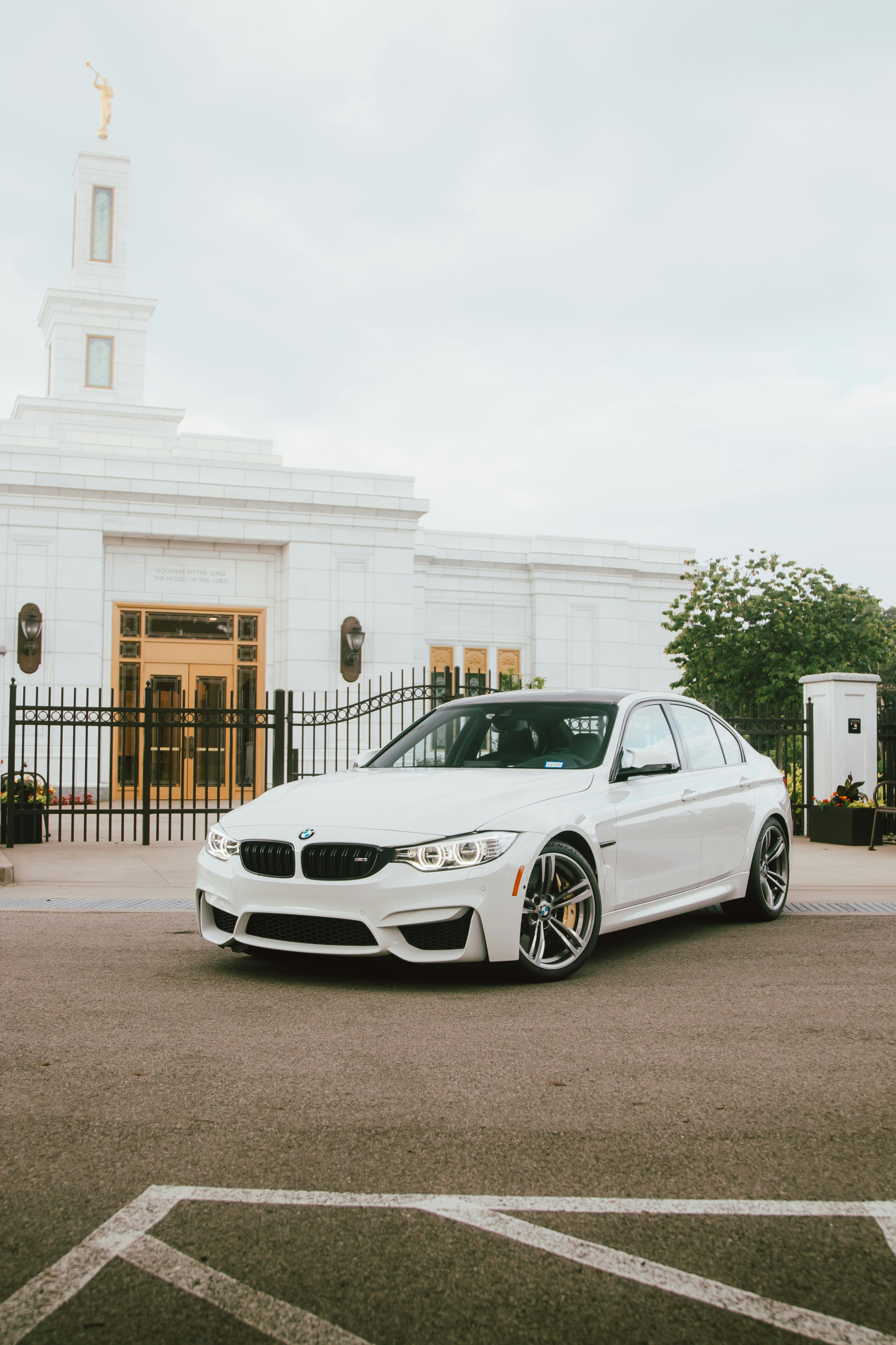 A white BMW sits outside a white building.