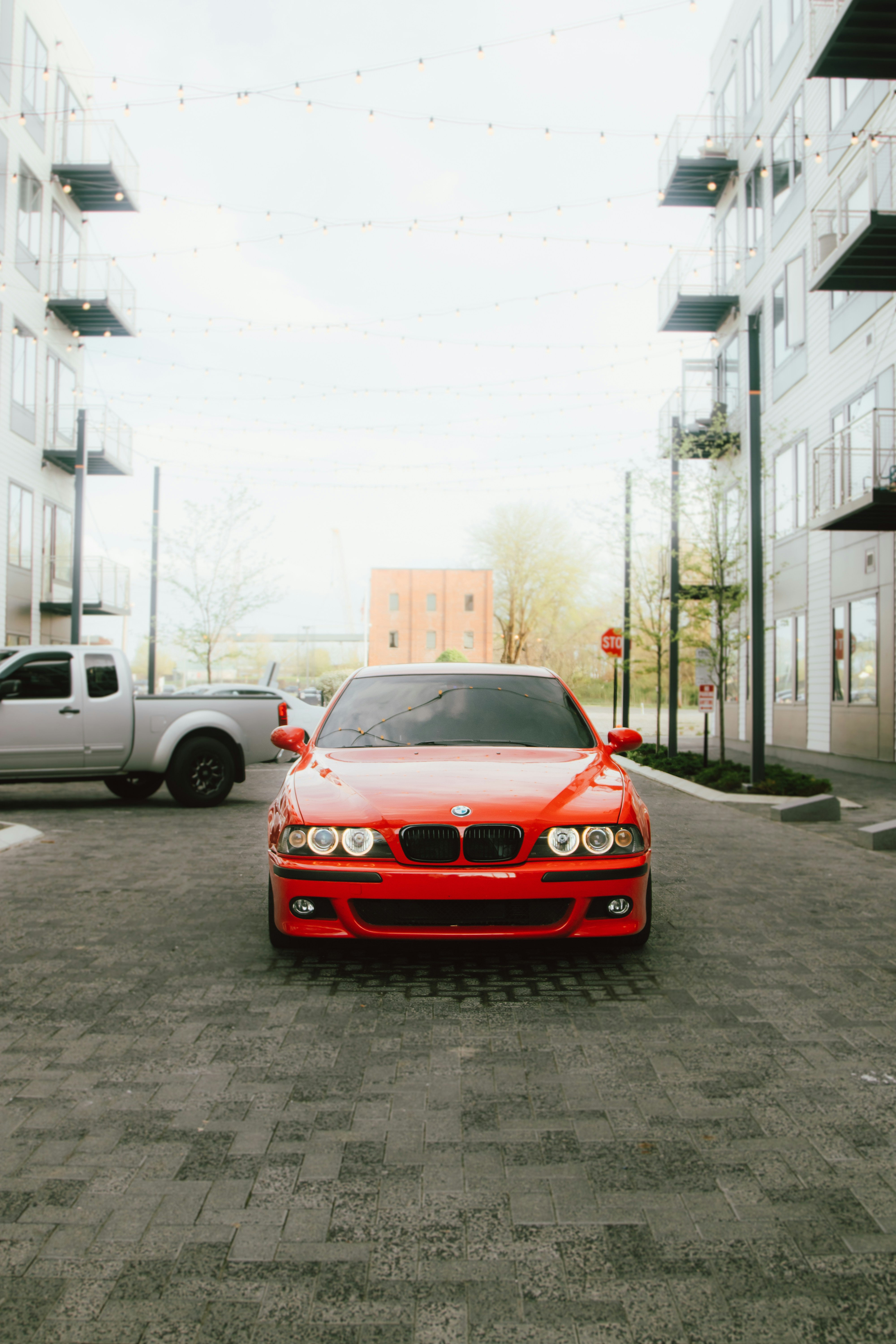 A red BMW parked between buildings.