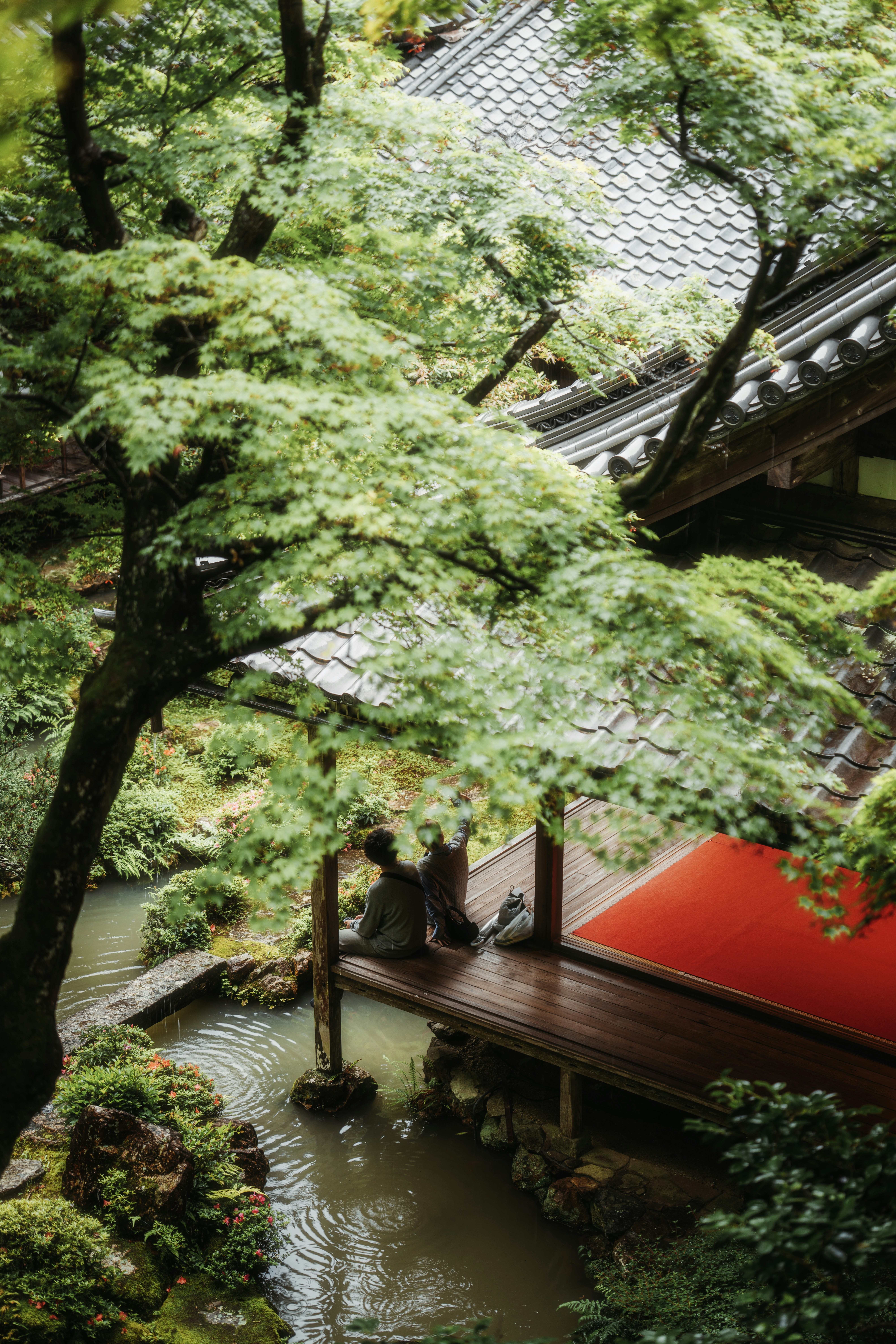 People sit near water in a japanese garden.