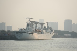 A white ship is docked in front of a city.