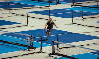 A man plays pickleball on an outdoor court.